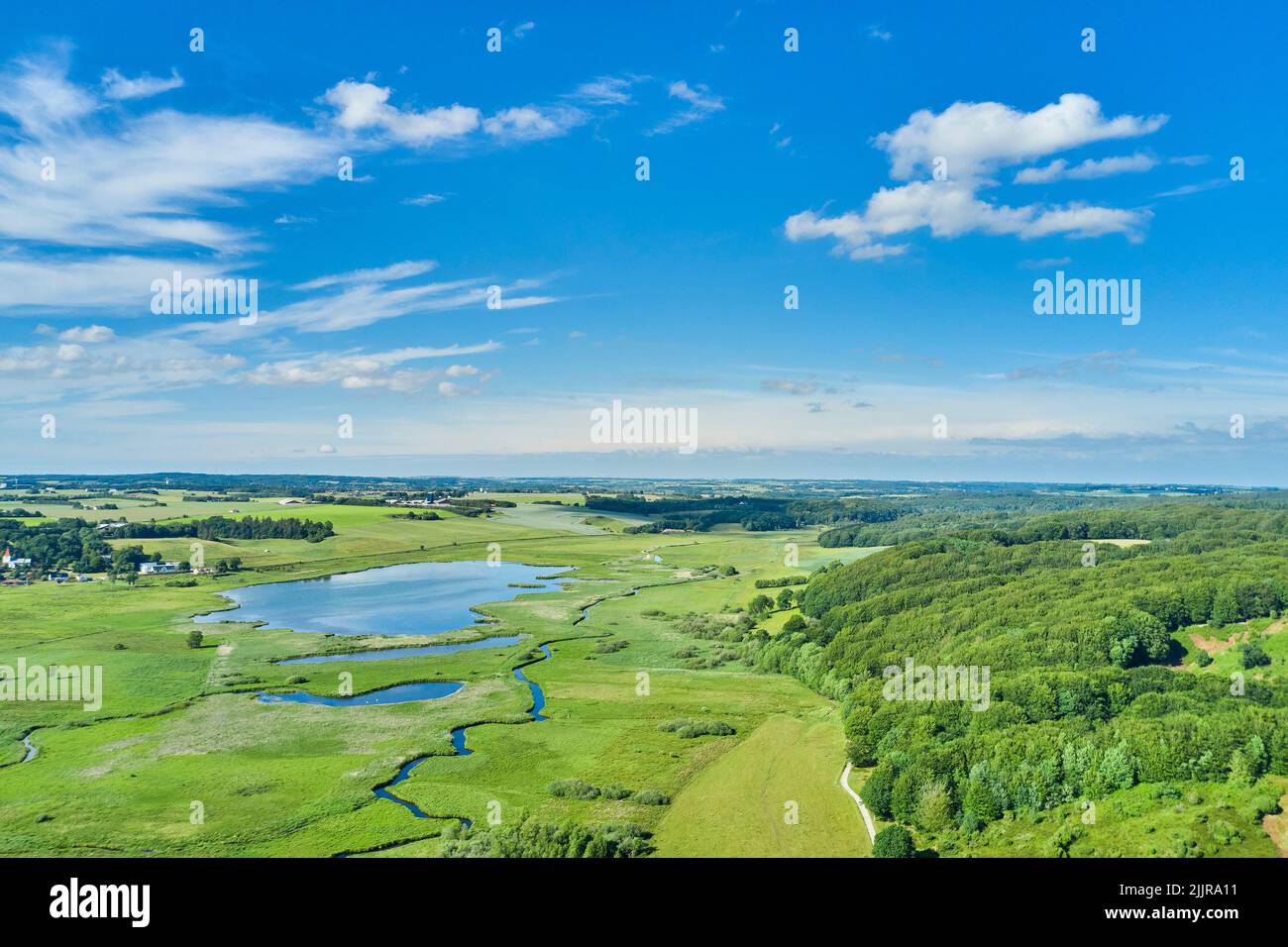 Paesaggio di campagna bello, verde e aperto con un lago, erba, e gli alberi che circondano le case coloniche. Vista aerea del terreno agricolo o eco-pulito Foto Stock