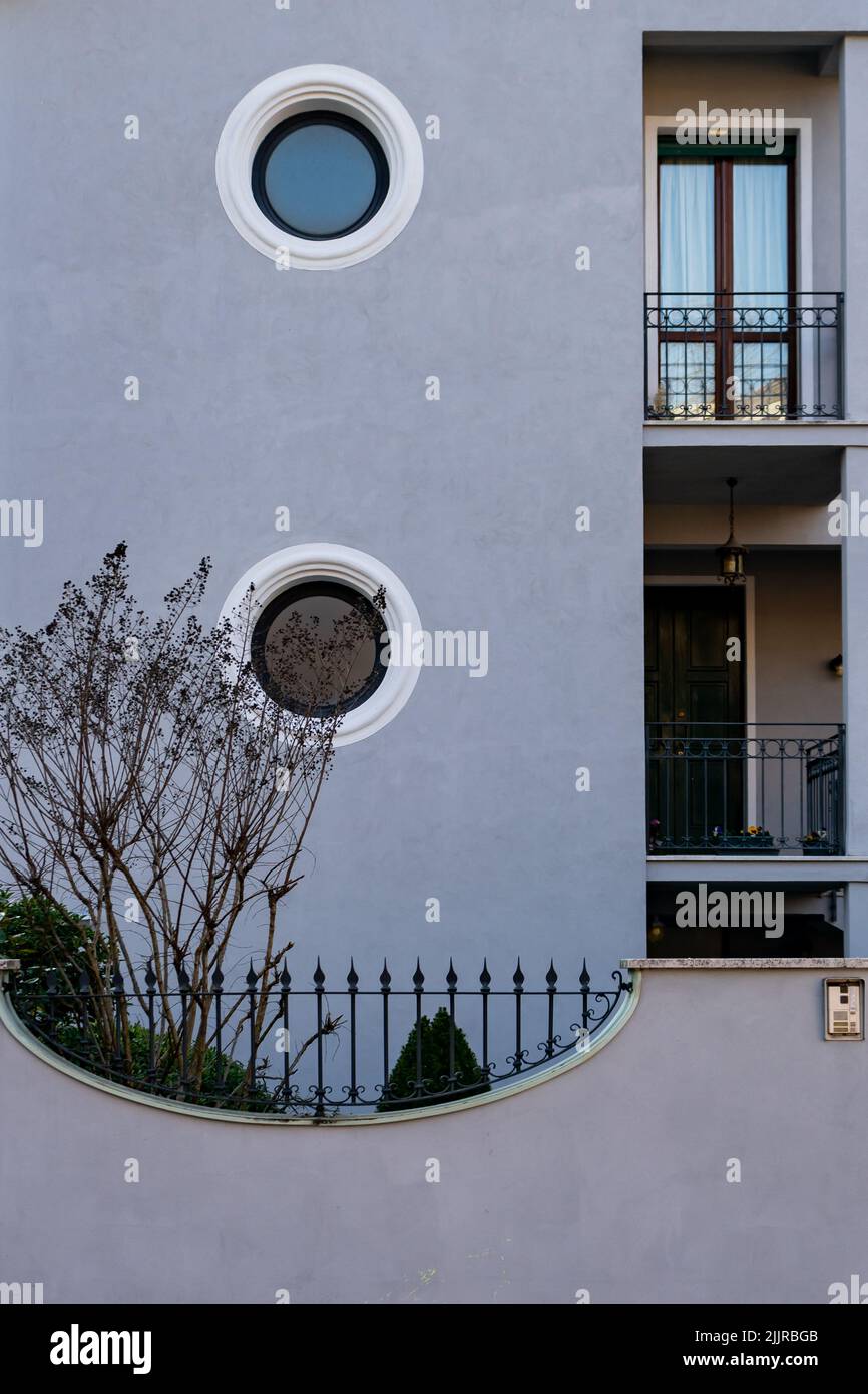Un colpo verticale di una casa grigia con finestre circolari durante il giorno Foto Stock