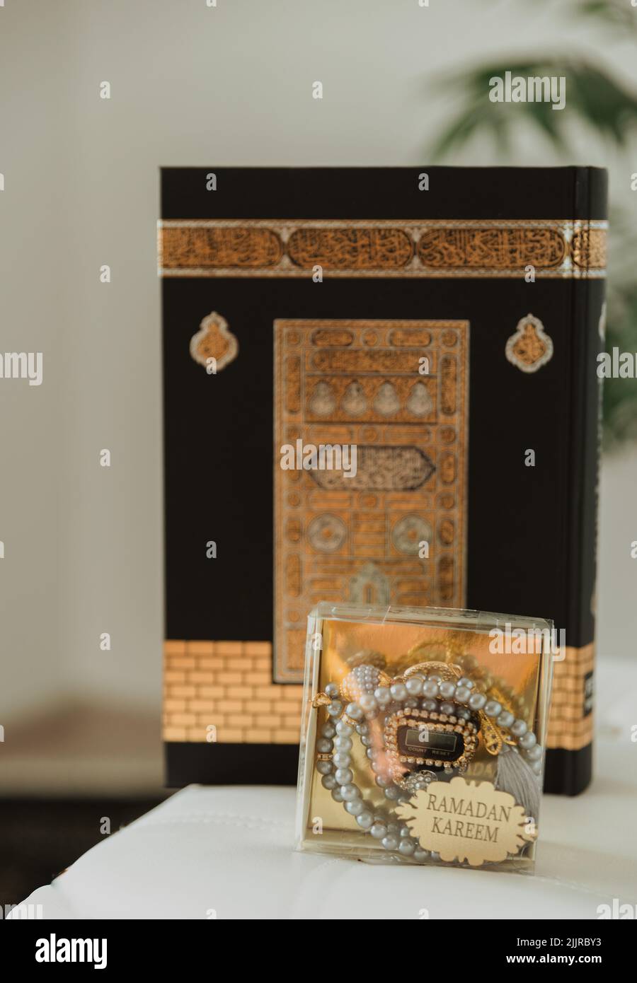 Un colpo verticale di un velluto nero Quran, decorato con motivo Kaaba e rosario fatto di perle con l'iscrizione Ramadan Kareem Foto Stock