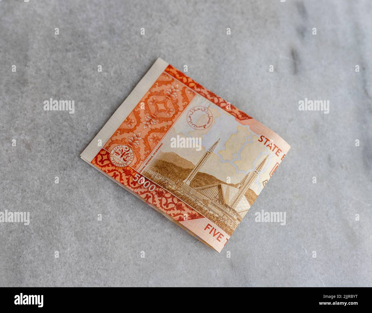 Banconote pakistane di 5000 rupie isolate su sfondo marmoreo. Foto Stock