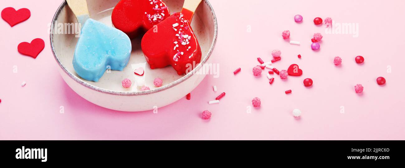 Diversi tipi di gelato a forma di popsicle su sfondo rosa. Atmosfera estiva. Panorama Foto Stock