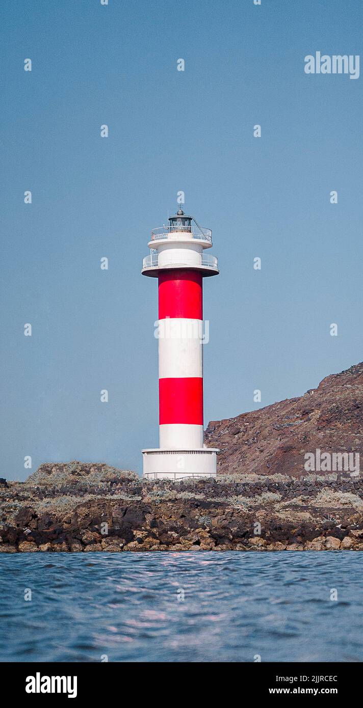 Un colpo verticale di faro rosso e bianco dal mare Foto Stock