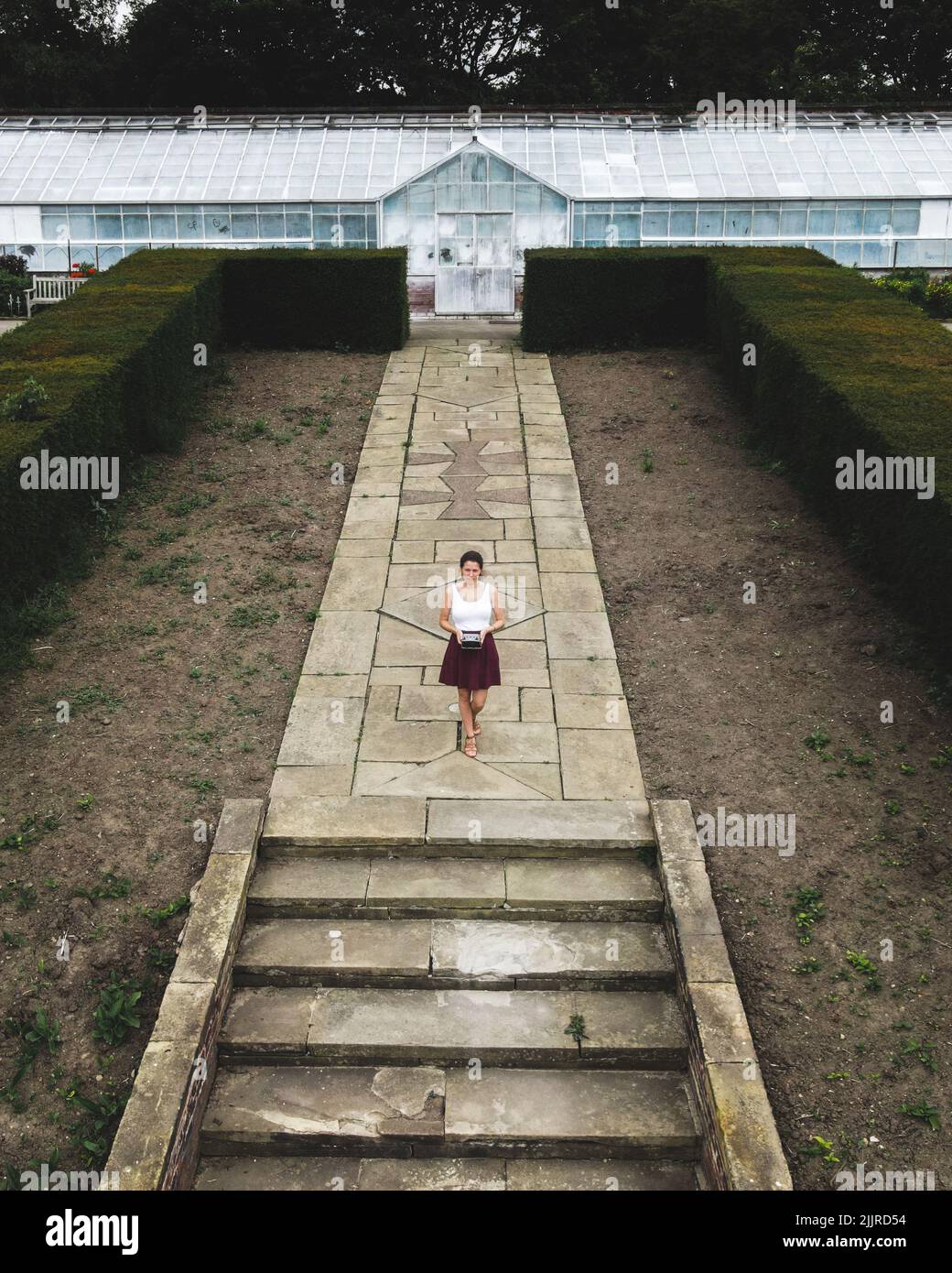 Giovane donna in piedi di fronte a un padiglione di vetro a Temple Newsam, foto drone, Leeds, Inghilterra, Regno Unito Foto Stock