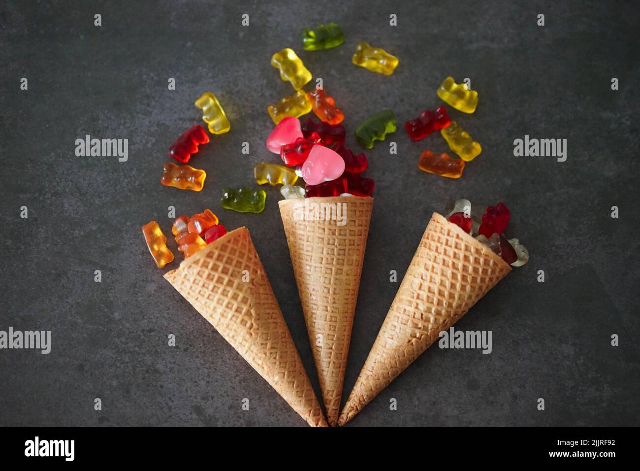 Un primo piano di tre coni gelato con orsacchiotti sulla superficie scura Foto Stock