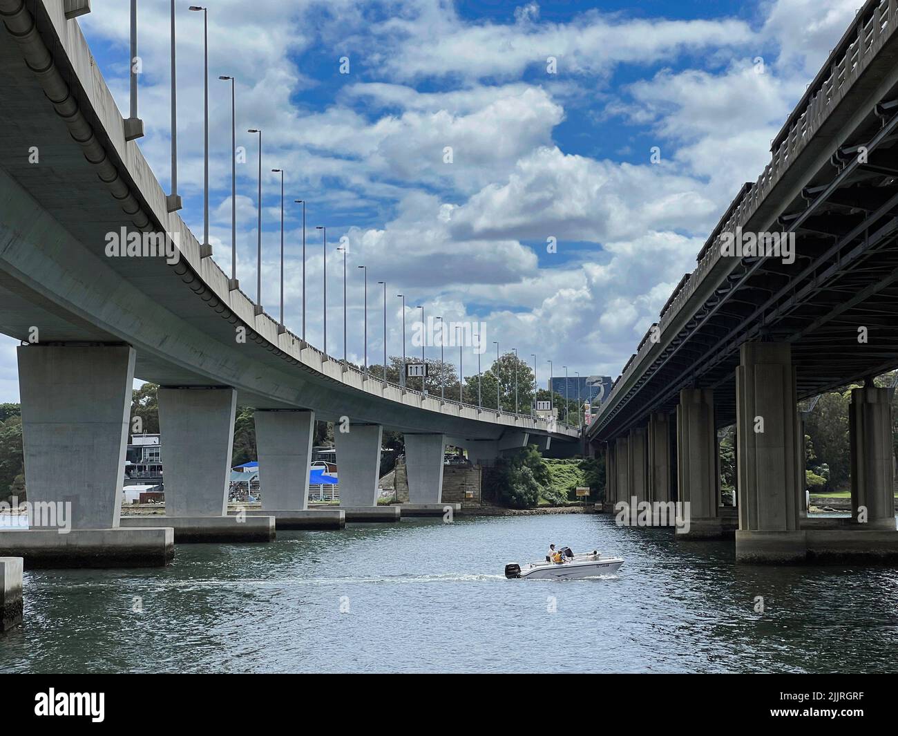 Una barca che naviga sotto il ponte pedonale Iron Cove Creek e Iron Cove Bridge a Bay Run Foto Stock