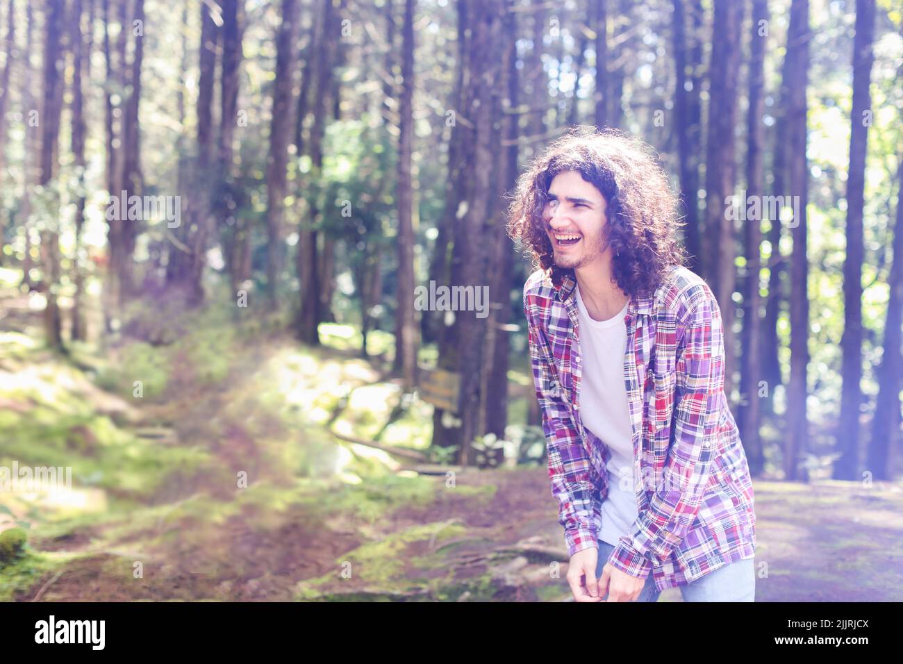 Giovane uomo latino-americano nella foresta guardando a sinistra con un'espressione ridente al Costa Rica Foto Stock