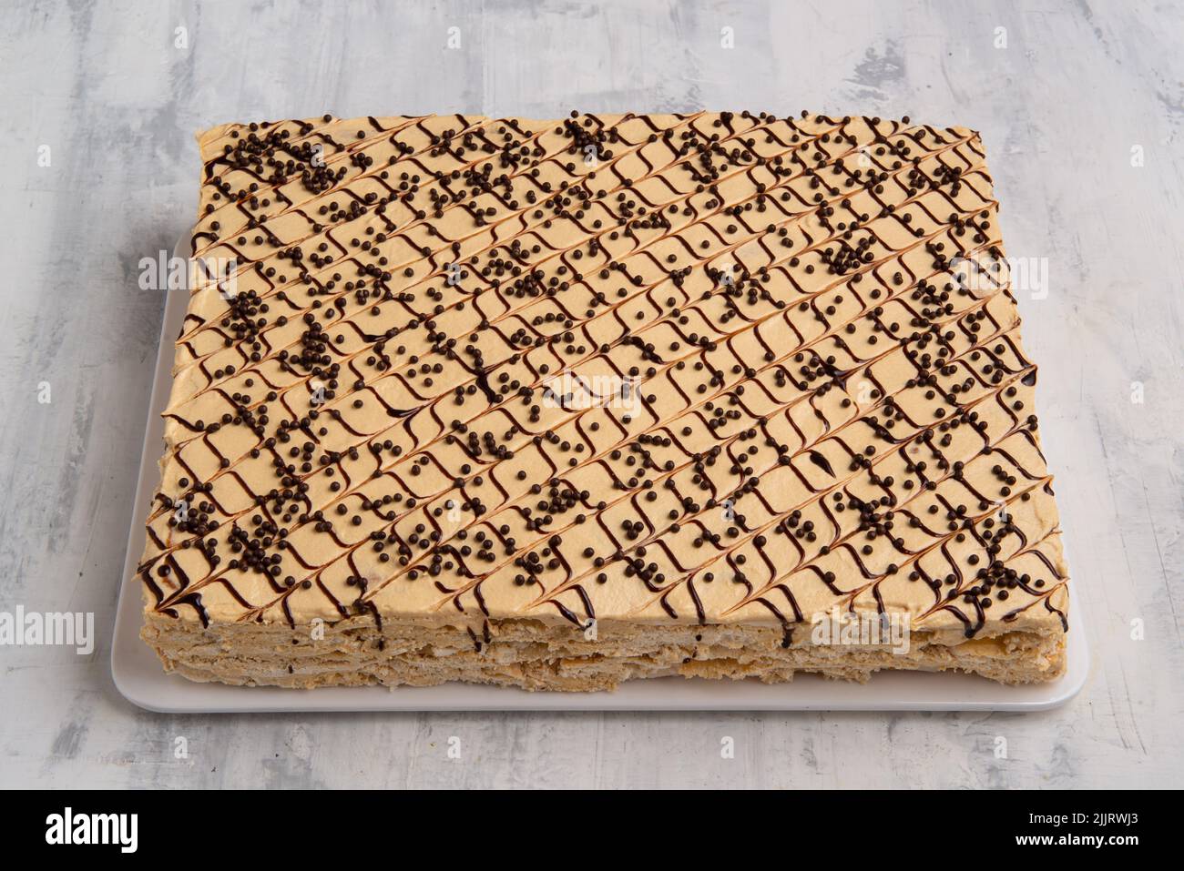 Una vista dall'alto di una piccola torta quadrata decorata con linee di cioccolato bianco e cioccolato nero Foto Stock