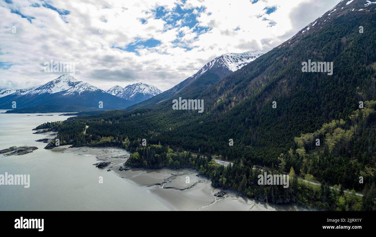 Una vista aerea di una catena montuosa innevata coperta di nuvole contro un lago nella speranza, Alaska Foto Stock