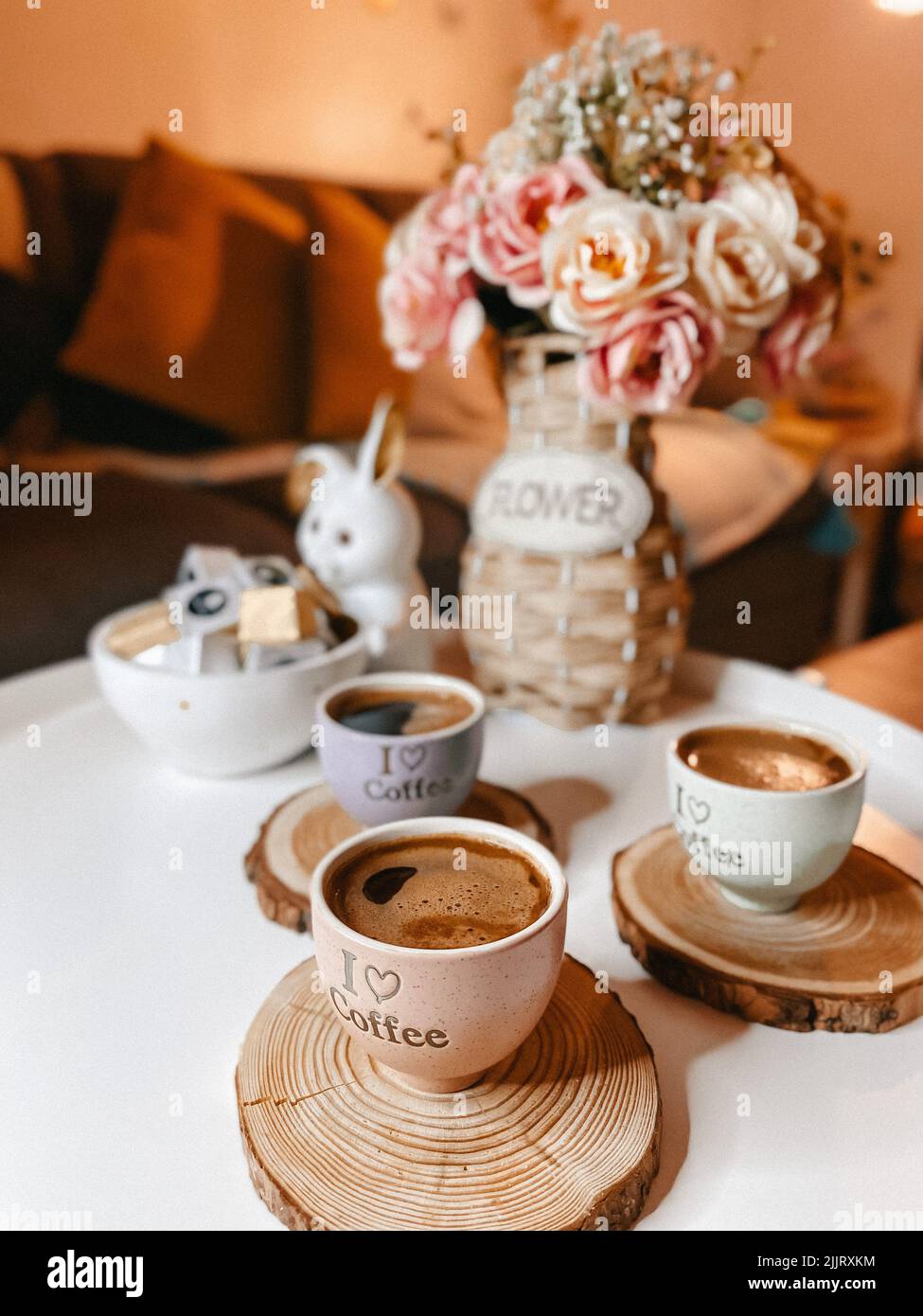 Una verticale di tazze di caffè ben disposte su un tavolo decorato con fiori Foto Stock