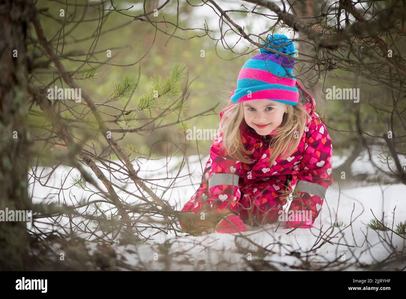 Una bambina caucasica carina in un inverno rosa generale e cappello giocare in un parco innevato Foto Stock