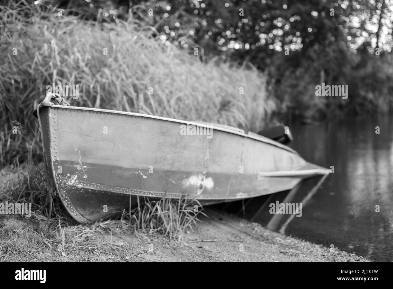 Una barca a motore è parcheggiata sulla riva di un lago o di un fiume in serata al tramonto o al mattino presto. La barca si trova in un luogo tranquillo vicino alla canna Foto Stock