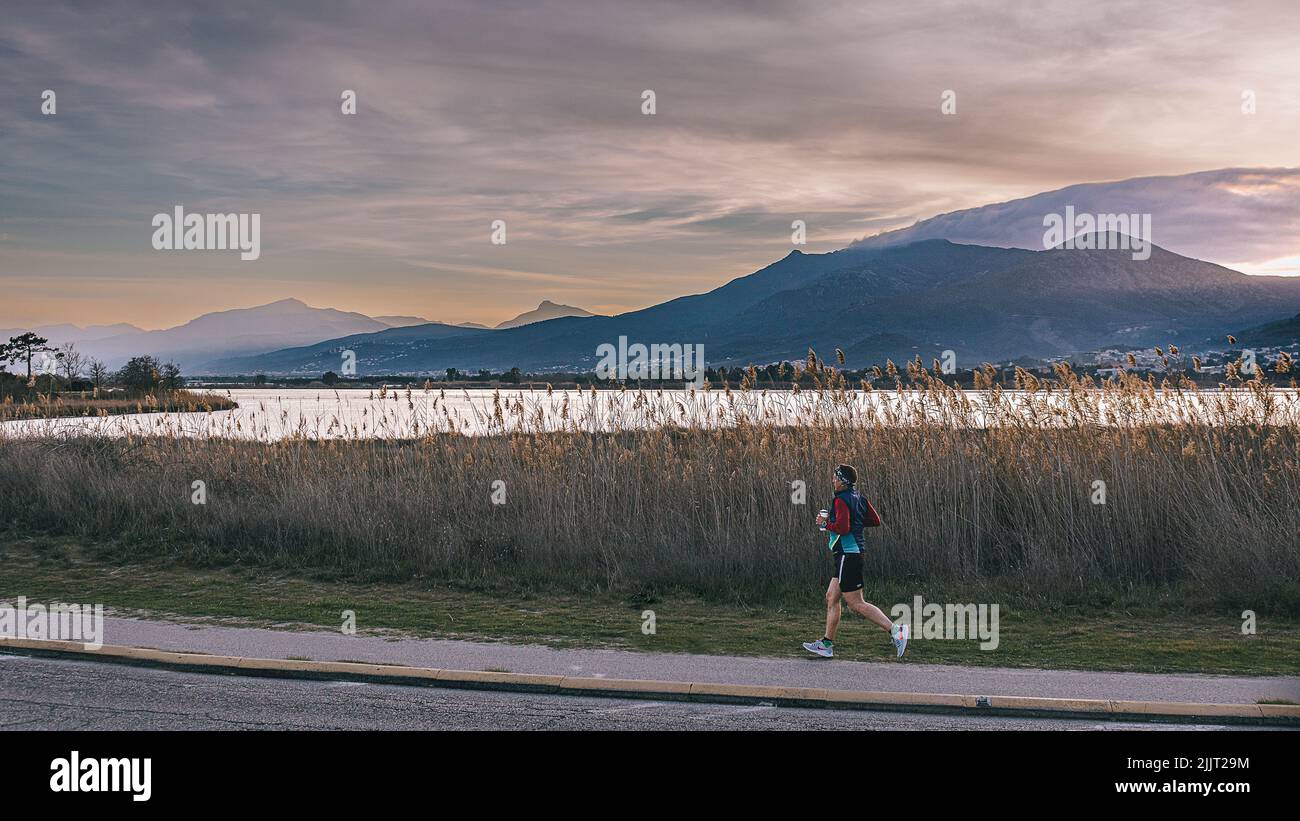 L'uomo che corre alla fine della giornata sullo stagno di Biguglia Corsica Foto Stock