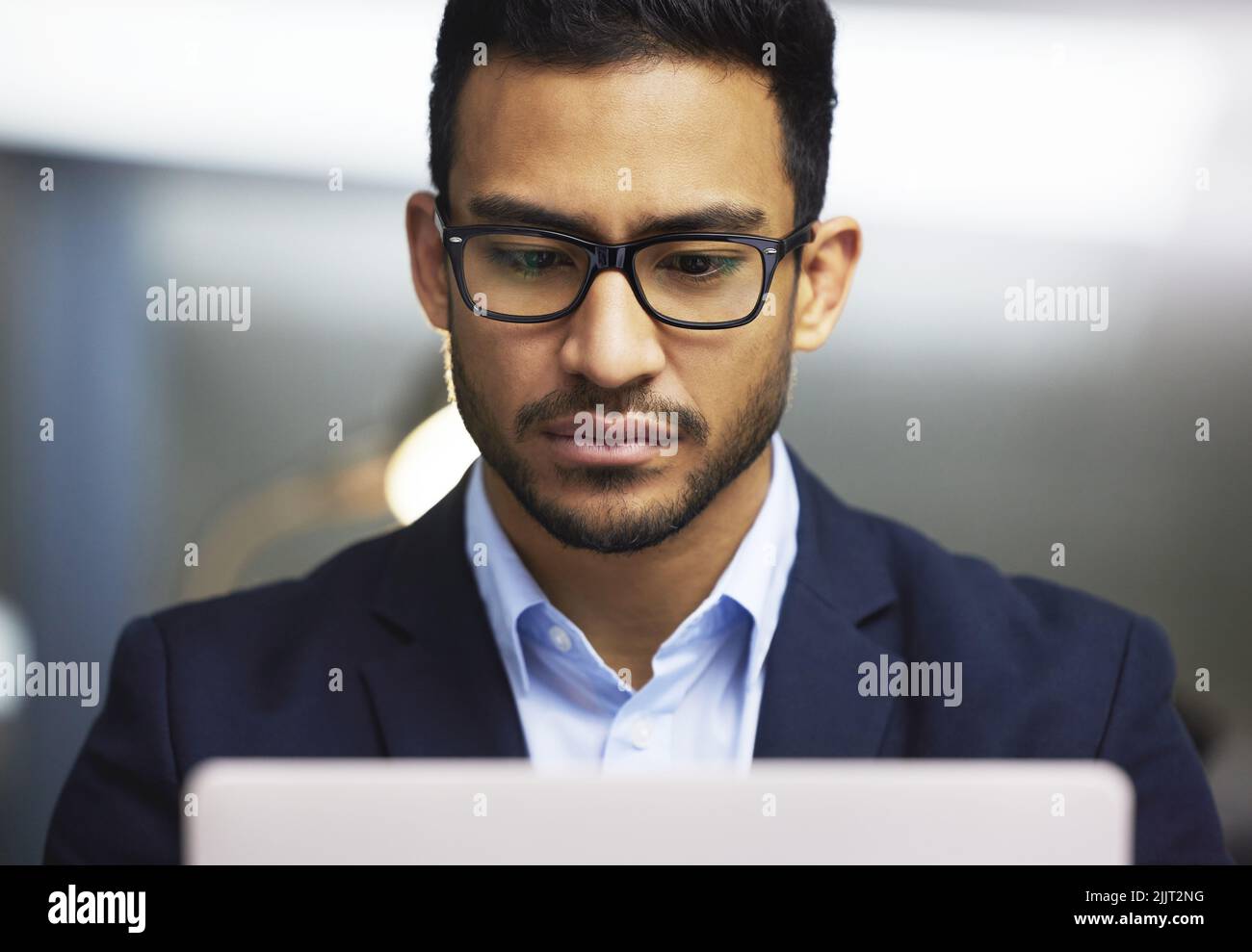 Vista frontale di un uomo d'affari concentrato che utilizza un laptop, trading sul mercato azionario. Operatore serio indossare occhiali e lavorare online con un computer Foto Stock