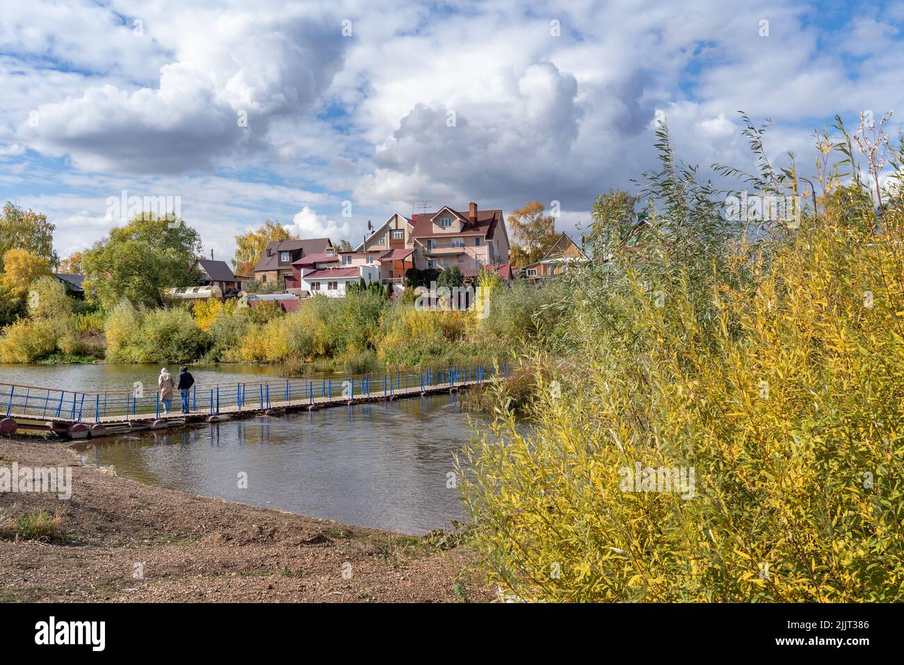 Paesaggio autunnale. Ponte sul fiume all'interno della città di Sterlitamak, Repubblica di Bashkortostan. Il fogliame dorato cresce sulla riva, sotto il cielo blu Foto Stock