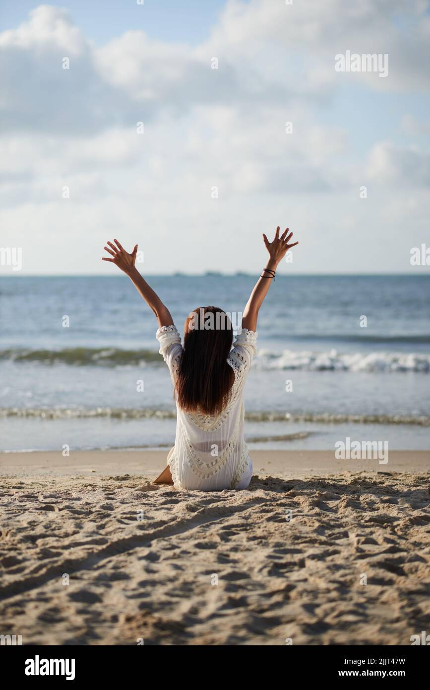 Vista posteriore della giovane donna che si gode il suo tempo sulla spiaggia Foto Stock