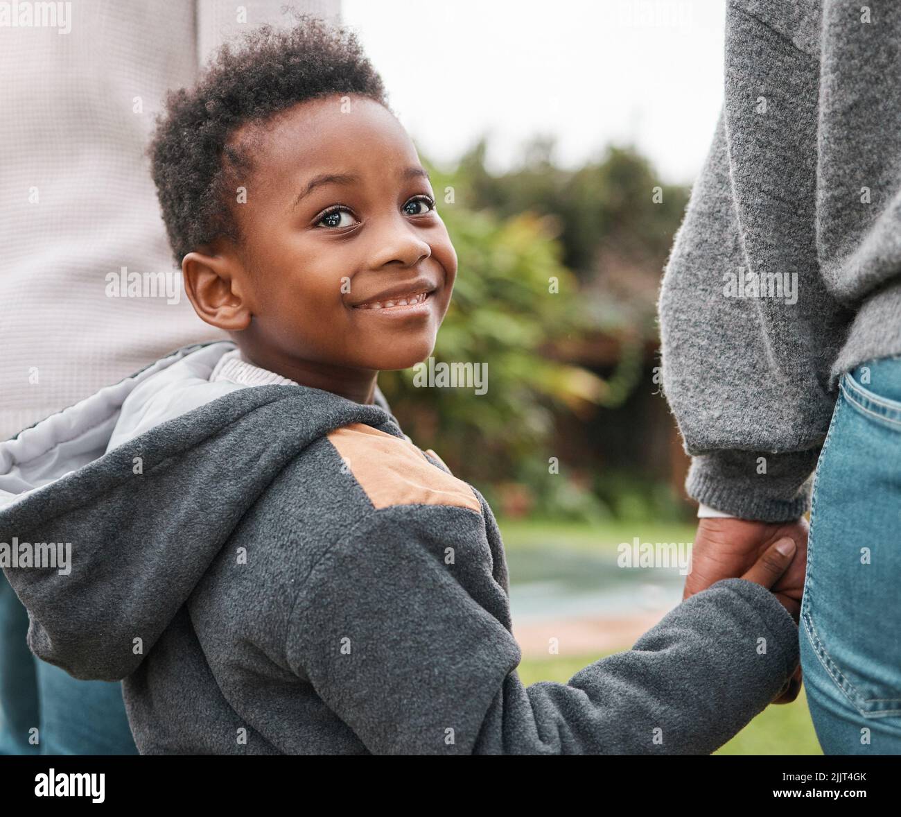 Ci seguirai in un'avventura, un adorabile ragazzino che tiene le mani dei genitori mentre cammina insieme all'aperto. Foto Stock