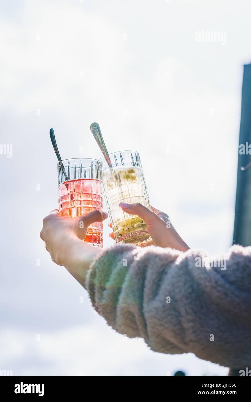 Uno shot verticale di una coppia che contiene bicchieri trasparenti pieni di cocktail e cucchiai su di essi Foto Stock