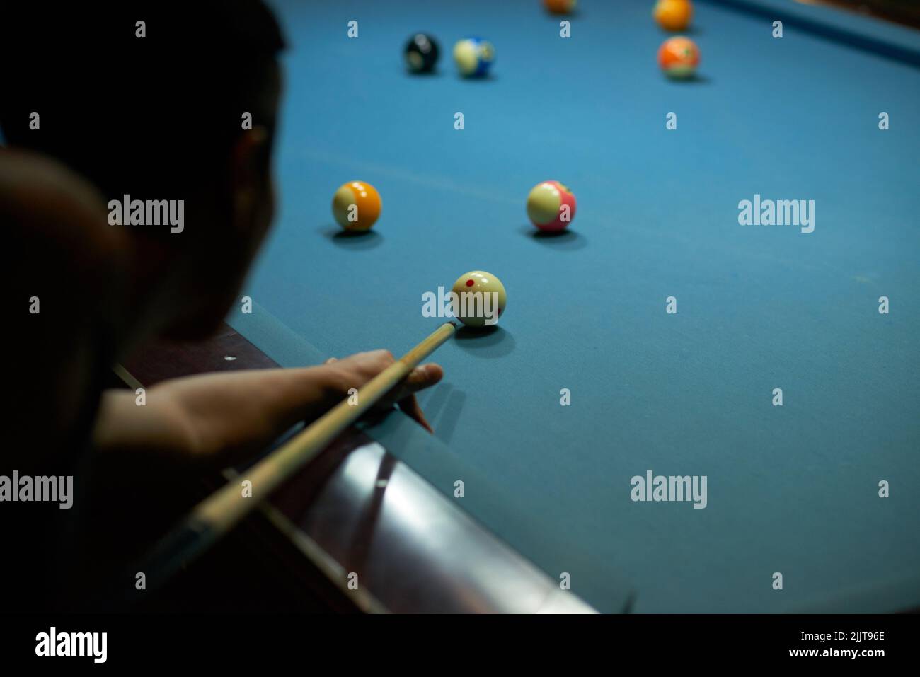 Giocatore di biliardo che colpisce il cue ball, vista sulla spalla Foto Stock