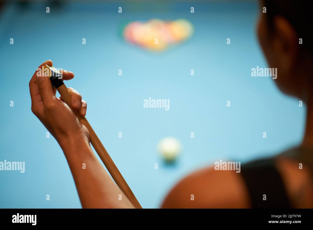 Donna che calca un cue di piscina prima del gioco Foto Stock