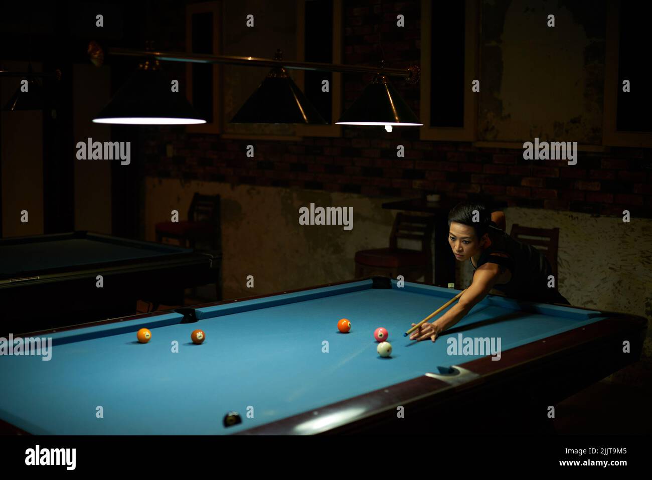 Donna vietnamita che gioca da sola nel club biliardo Foto Stock