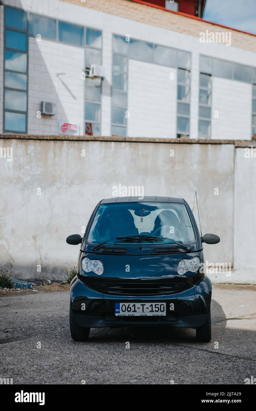 Uno scatto verticale di una Smart ForTwo nera nello spazio di parcheggio contro un edificio Foto Stock