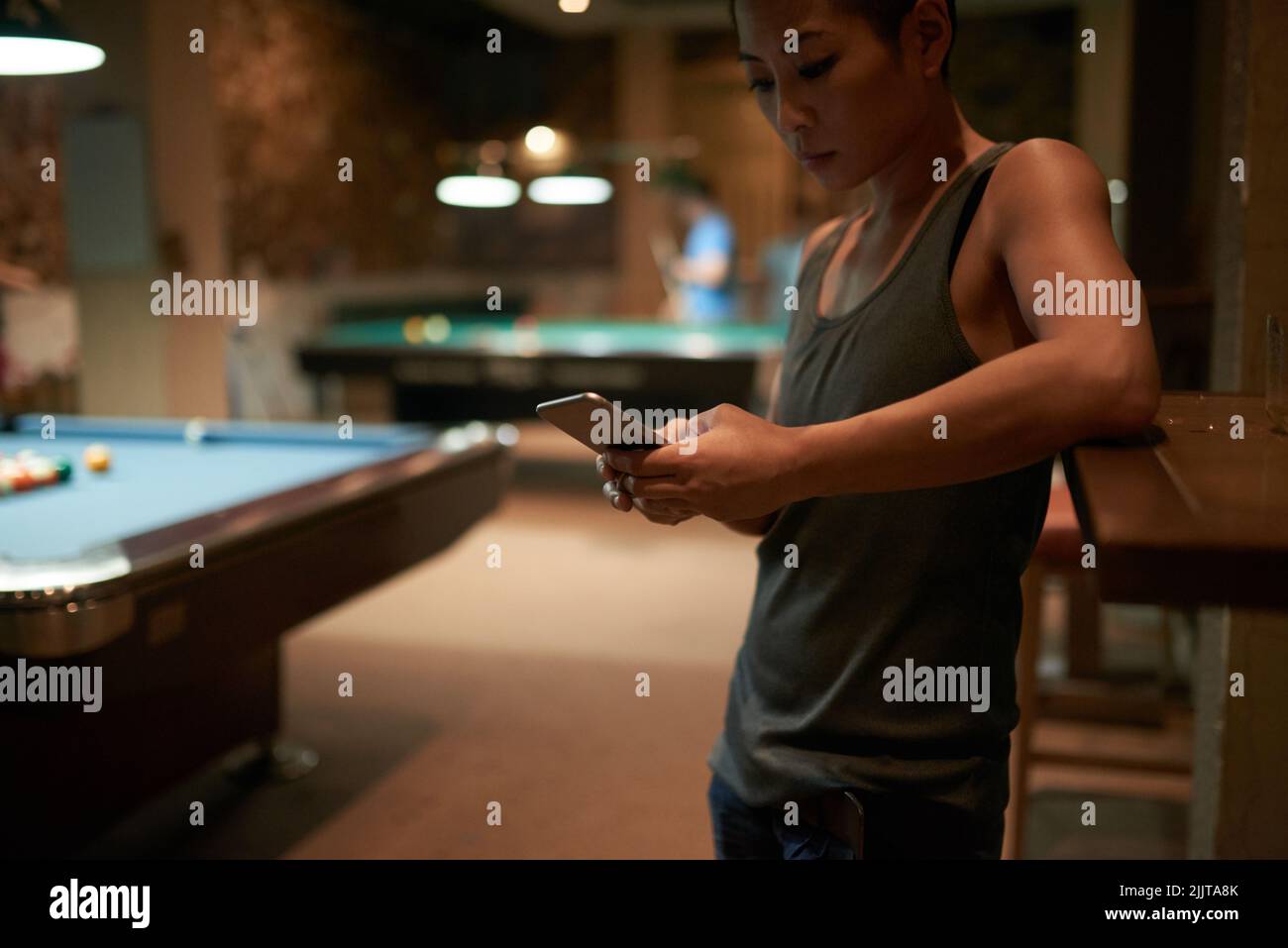 Donna che controlla il suo smartphone quando passa il tempo al bar Foto Stock