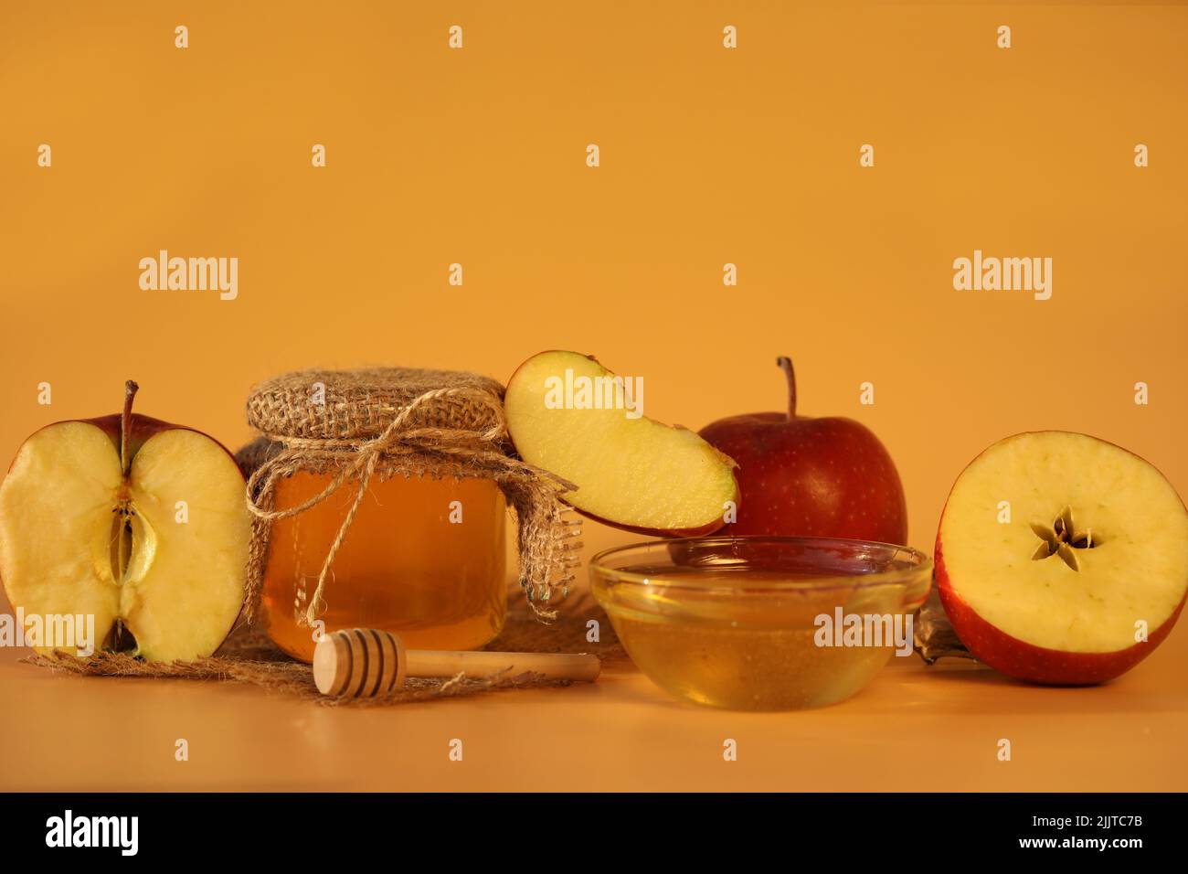 Mele fresche rosse con miele su sfondo giallo con spazio copia. Festa della mela Foto Stock