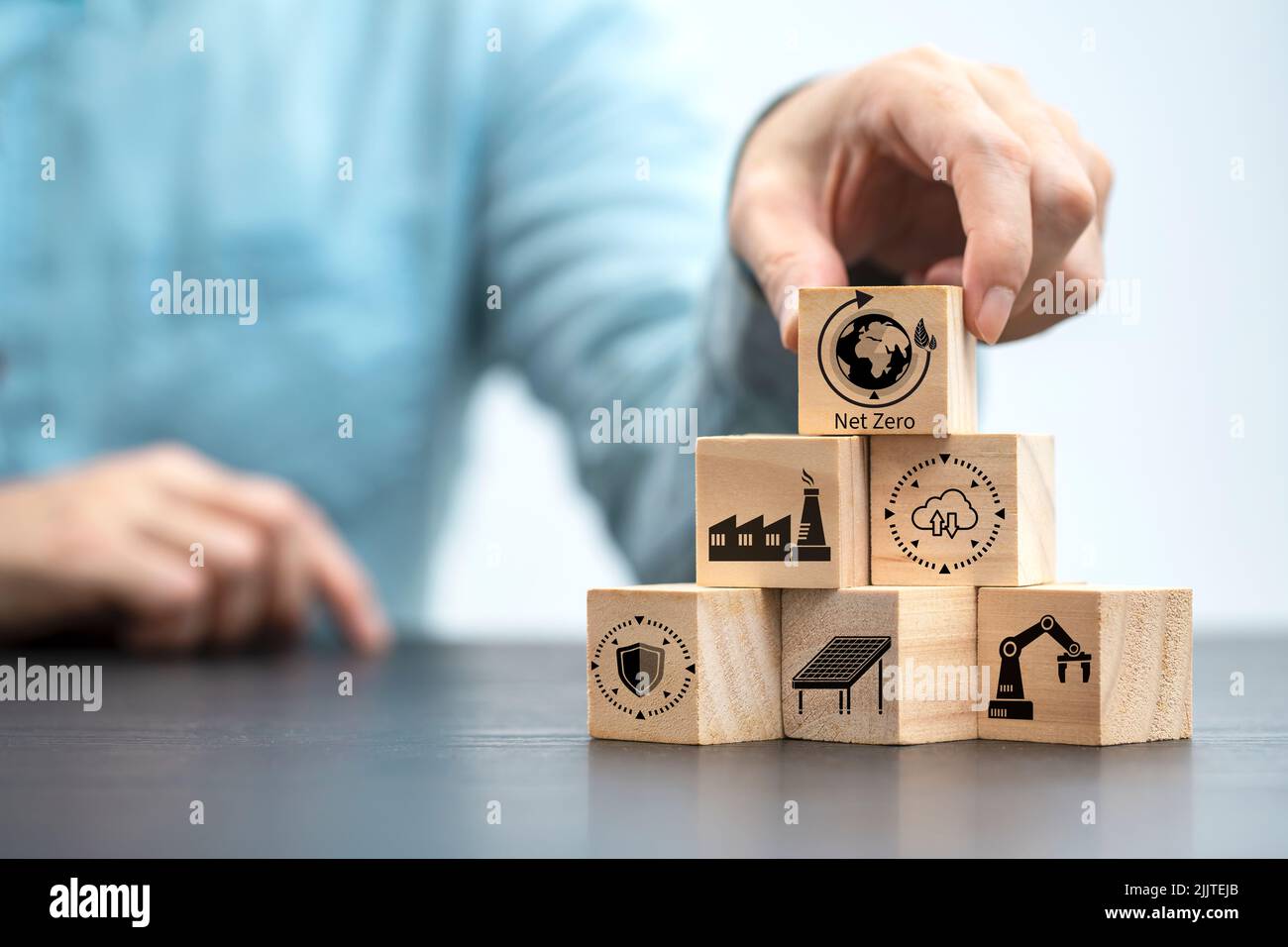 Businessman mano che arrangiano blocco di legno con icona zero netto , energia zero netto da 2050 carbonio neutro o obiettivo di emissione di gas serra zero netto su legno Foto Stock