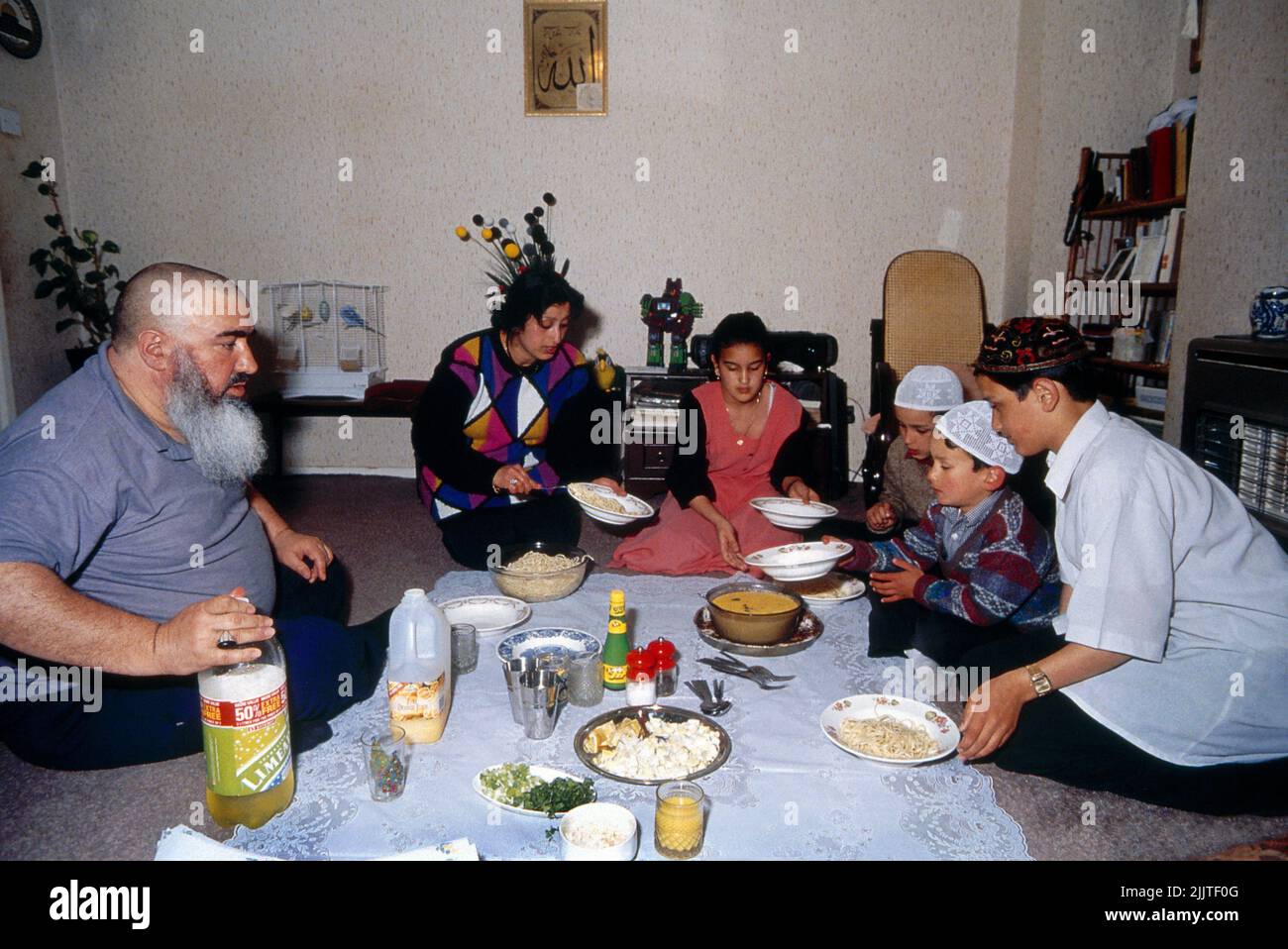 Famiglia musulmana che si rompe velocemente dopo Ramadan seduta sul pavimento che ha un pasto Clapton Londra Inghilterra Foto Stock