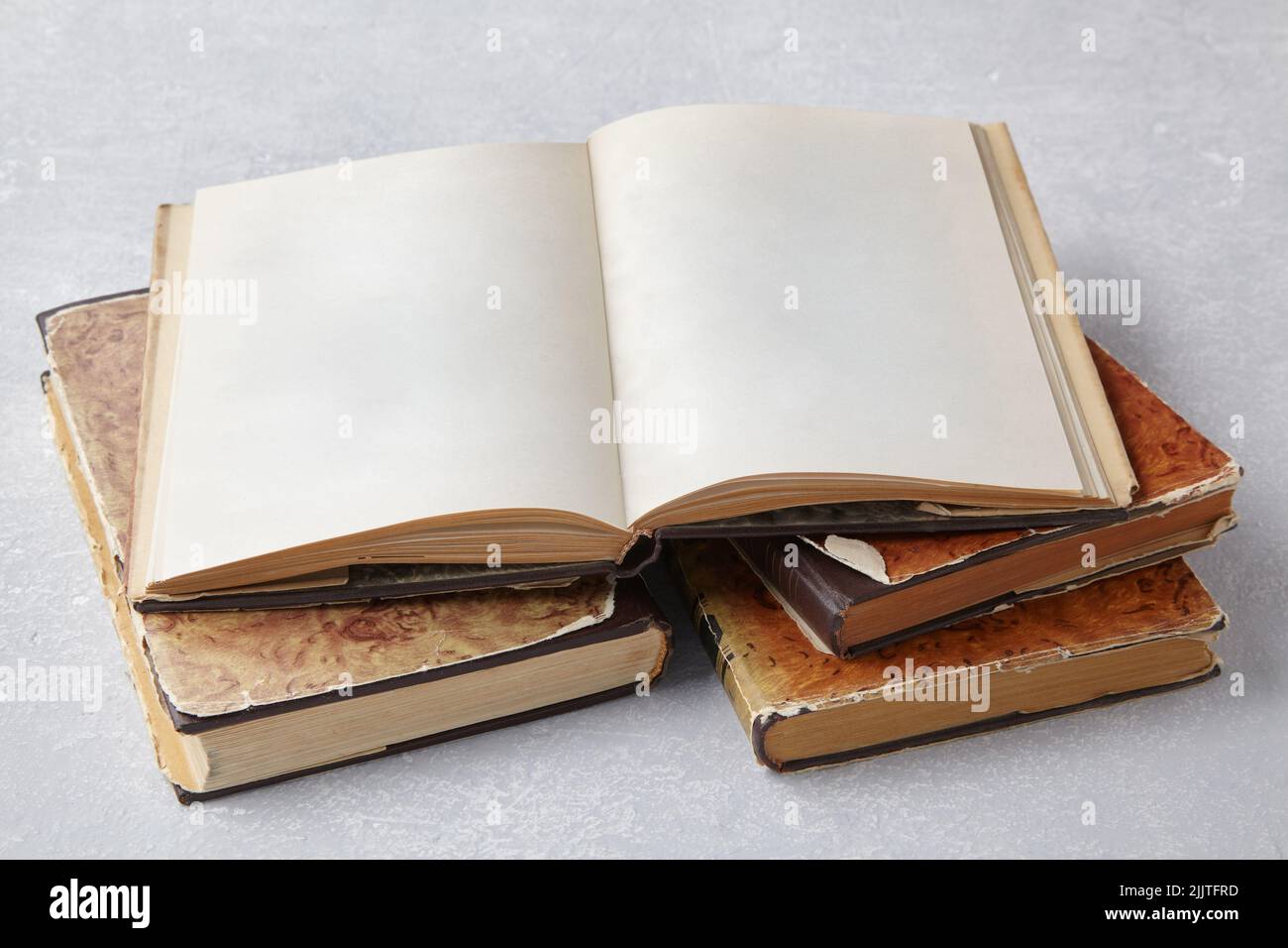 Apri un libro o un notebook vintage in una super giacca su una pila di vecchi libri shabby su un tavolo di cemento grigio chiaro Foto Stock