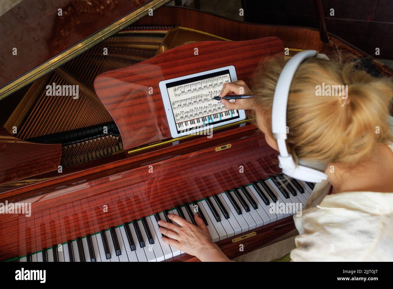 una giovane ragazza compositore, scrive musica su un tablet e suona il pianoforte. Concetto moderno Foto Stock