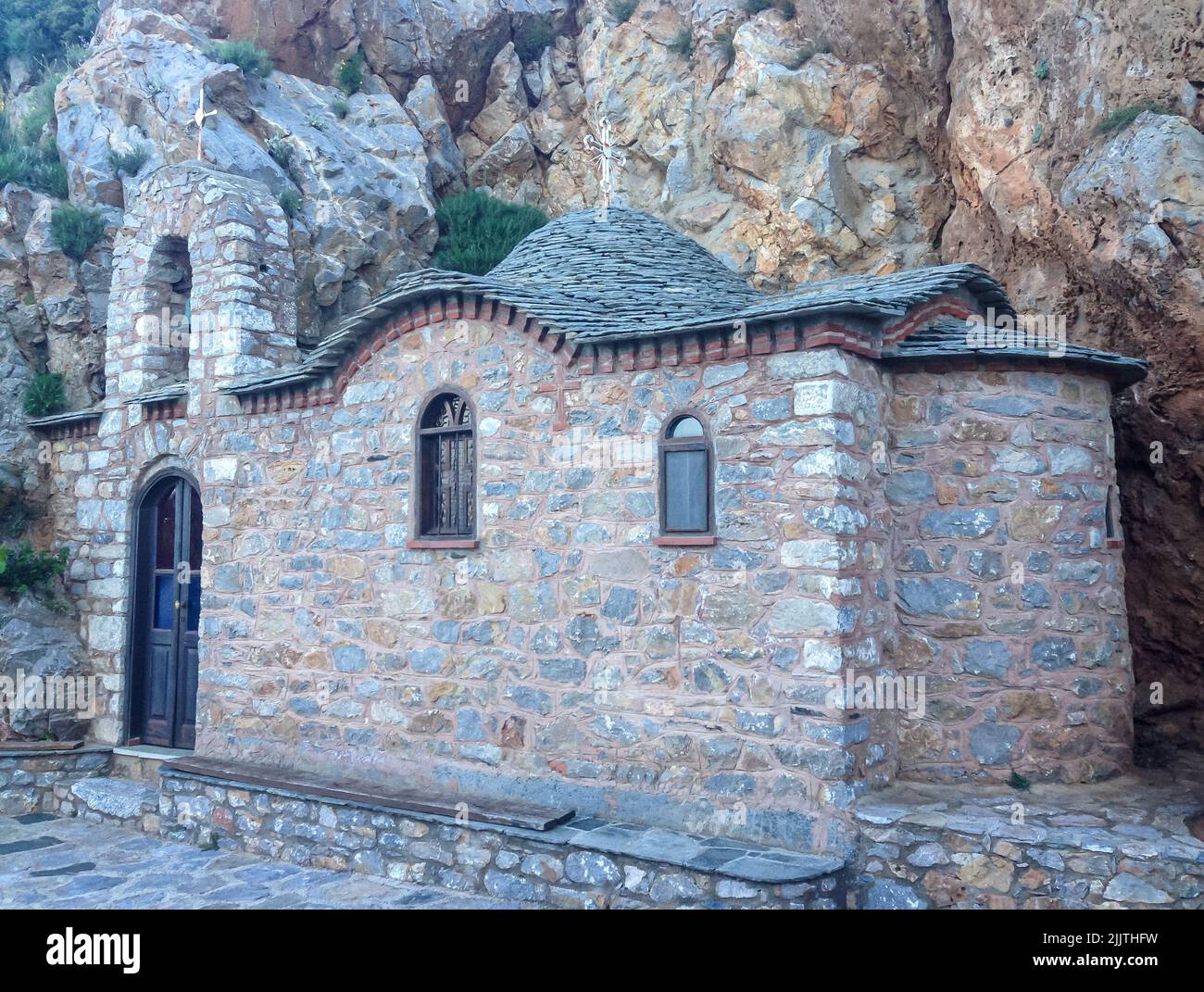 Una chiesa ortodossa orientale fatta di pietre sotto le rocce del Monte Athos, Grecia Foto Stock