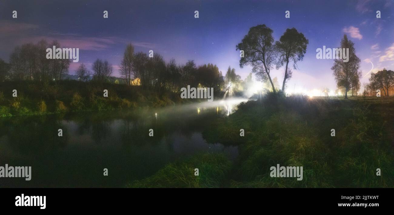 Una bella vista su un fiume Istra con grandi alberi di notte Foto Stock