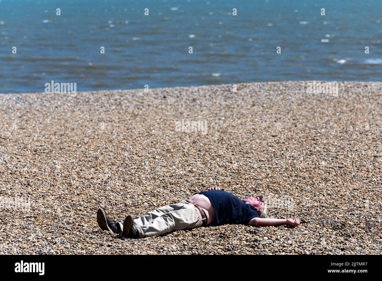 Uomo prendere il sole sulla spiaggia durante la calda estate del 2022 Foto Stock