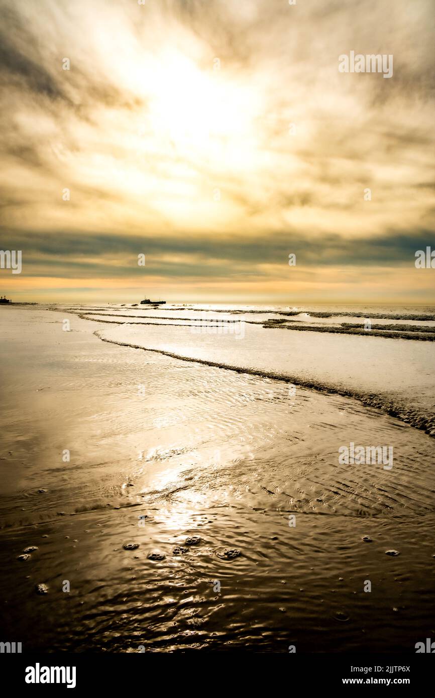 Incredibile tramonto colorato su una spiaggia di sabbia al mare sotto un cielo dipinto di nuvole e un sole dorato. Paesaggi naturali pittoreschi. Le nuvole si riflettono nell'acqua. Atmosfera tranquilla Zen-come nessun popolo. Spazio per il testo ispirato al viaggio. Foto di alta qualità Foto Stock