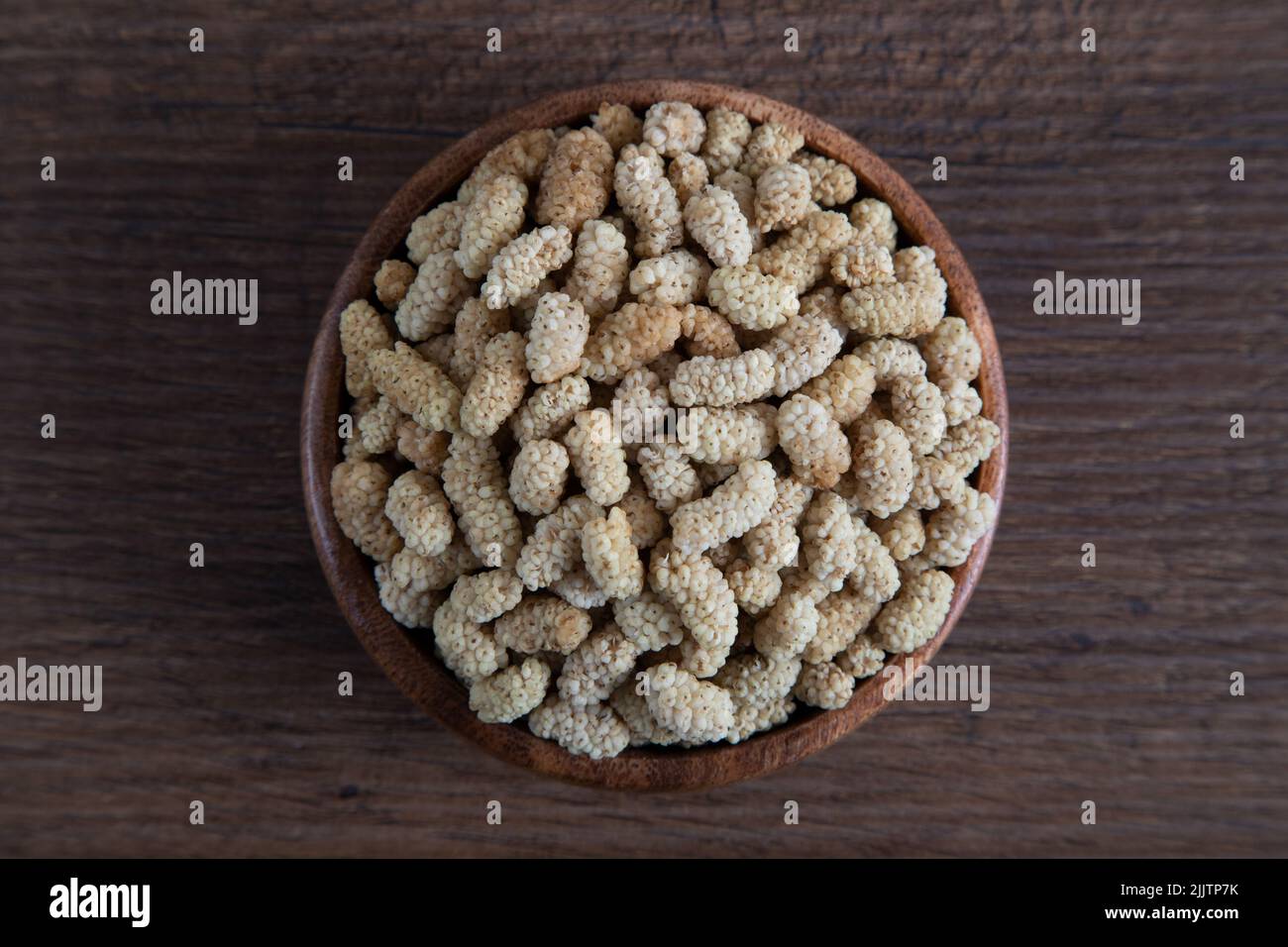 Ciotola piena di gelso secco su sfondo di legno Foto Stock