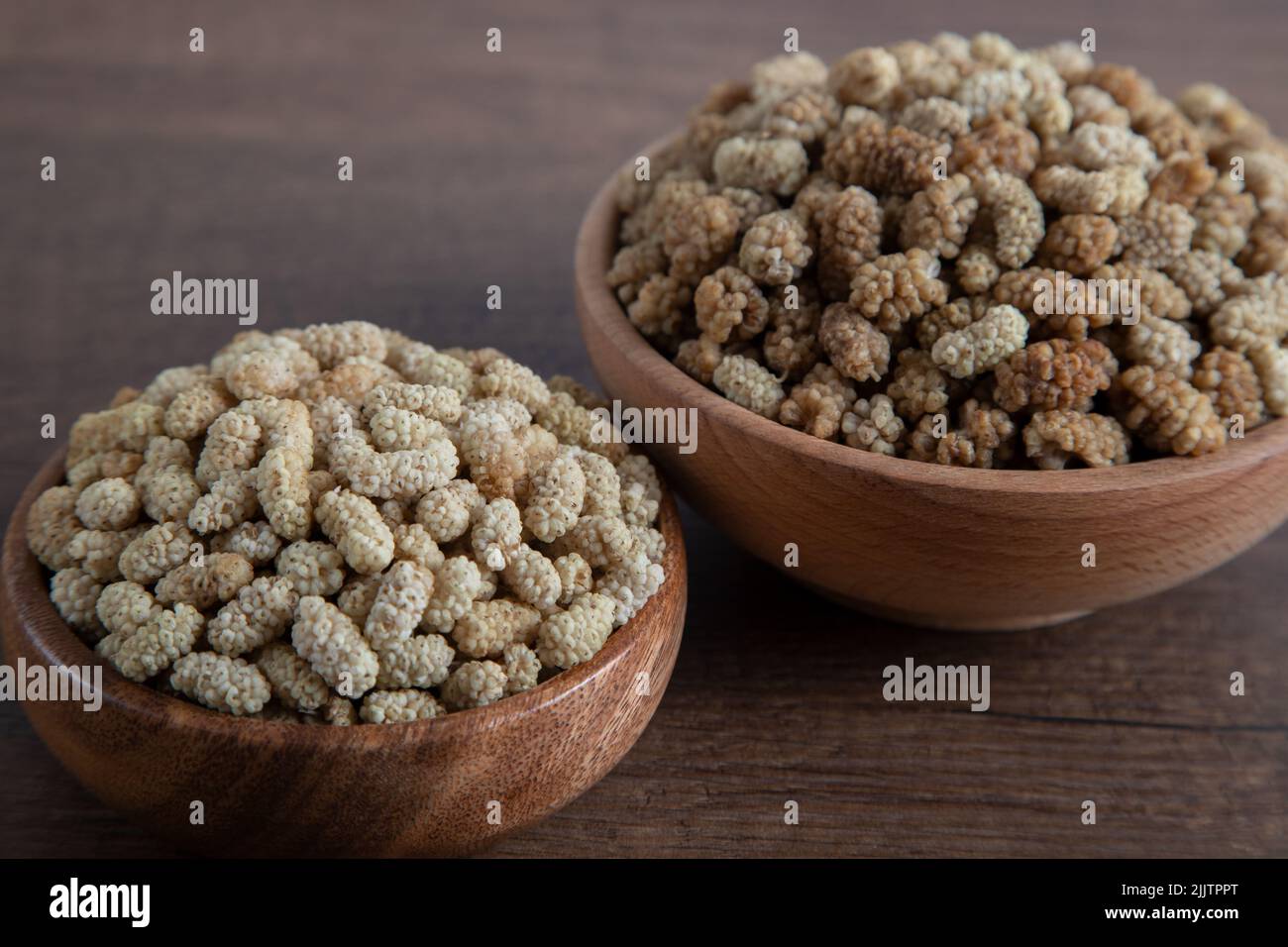 Ciotola piena di gelso secco su sfondo di legno Foto Stock