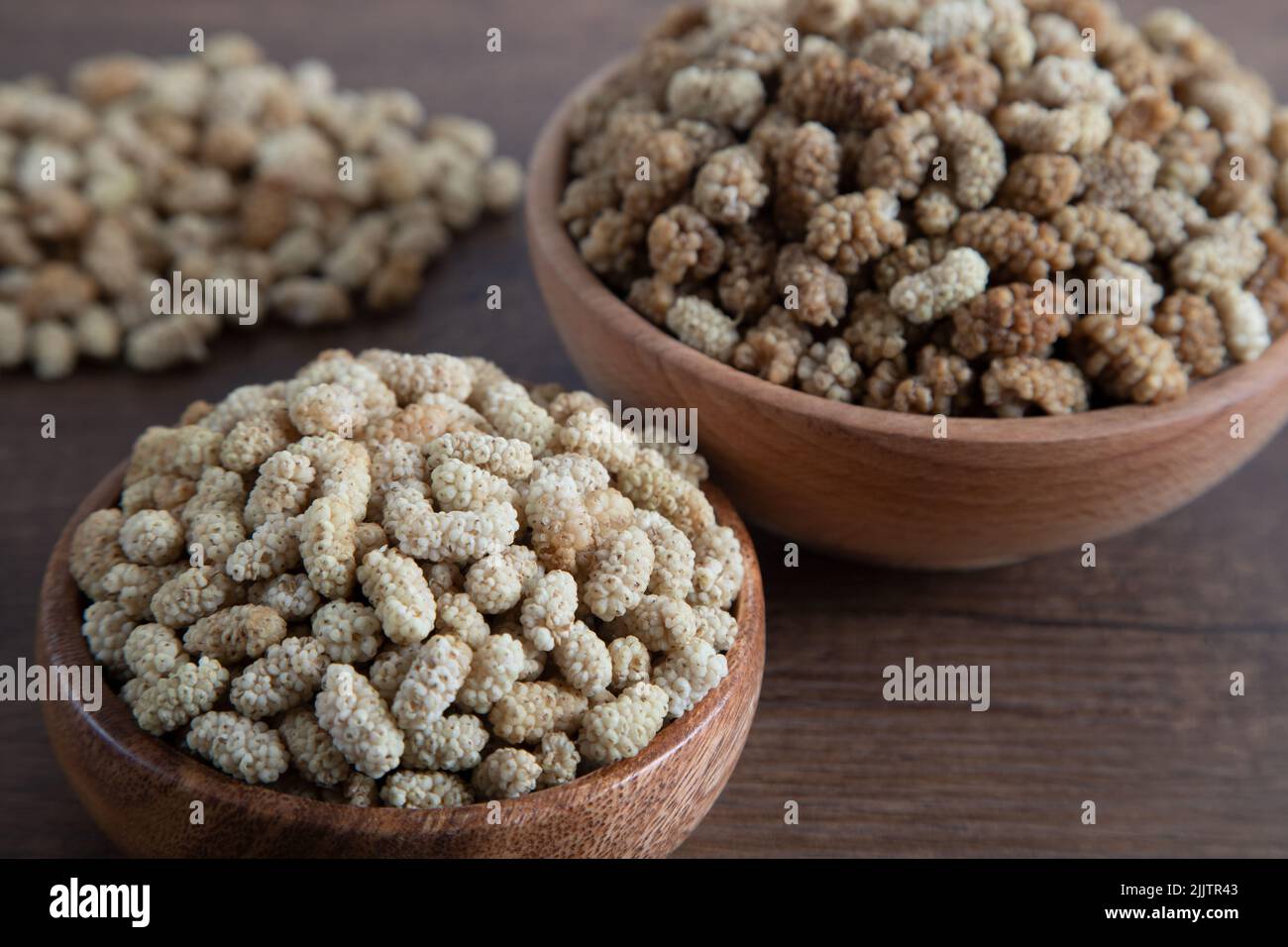 Ciotola piena di gelso secco su sfondo di legno Foto Stock
