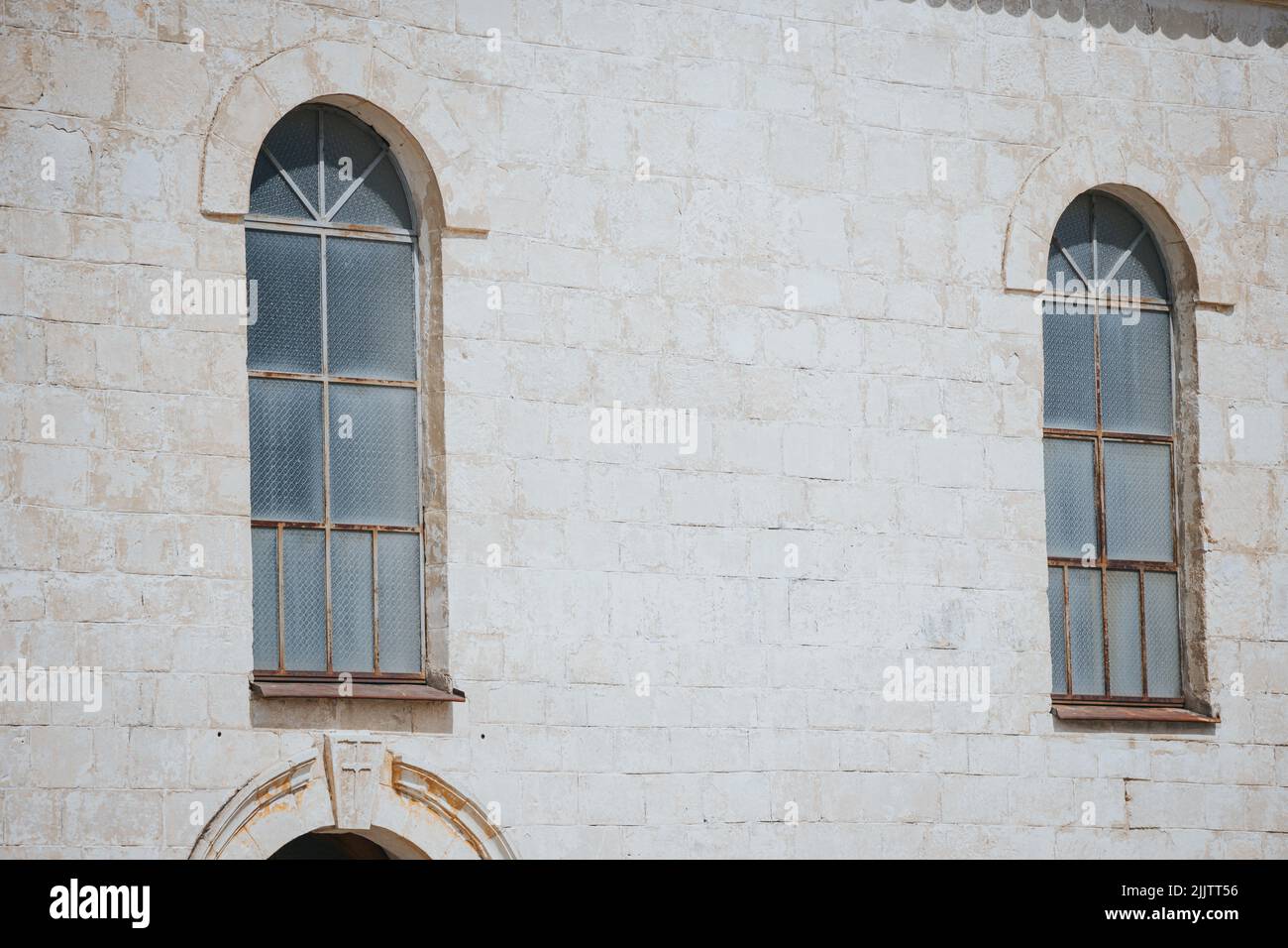 Un primo piano di due vecchie finestre ad arco di un edificio sotto la luce del sole Foto Stock