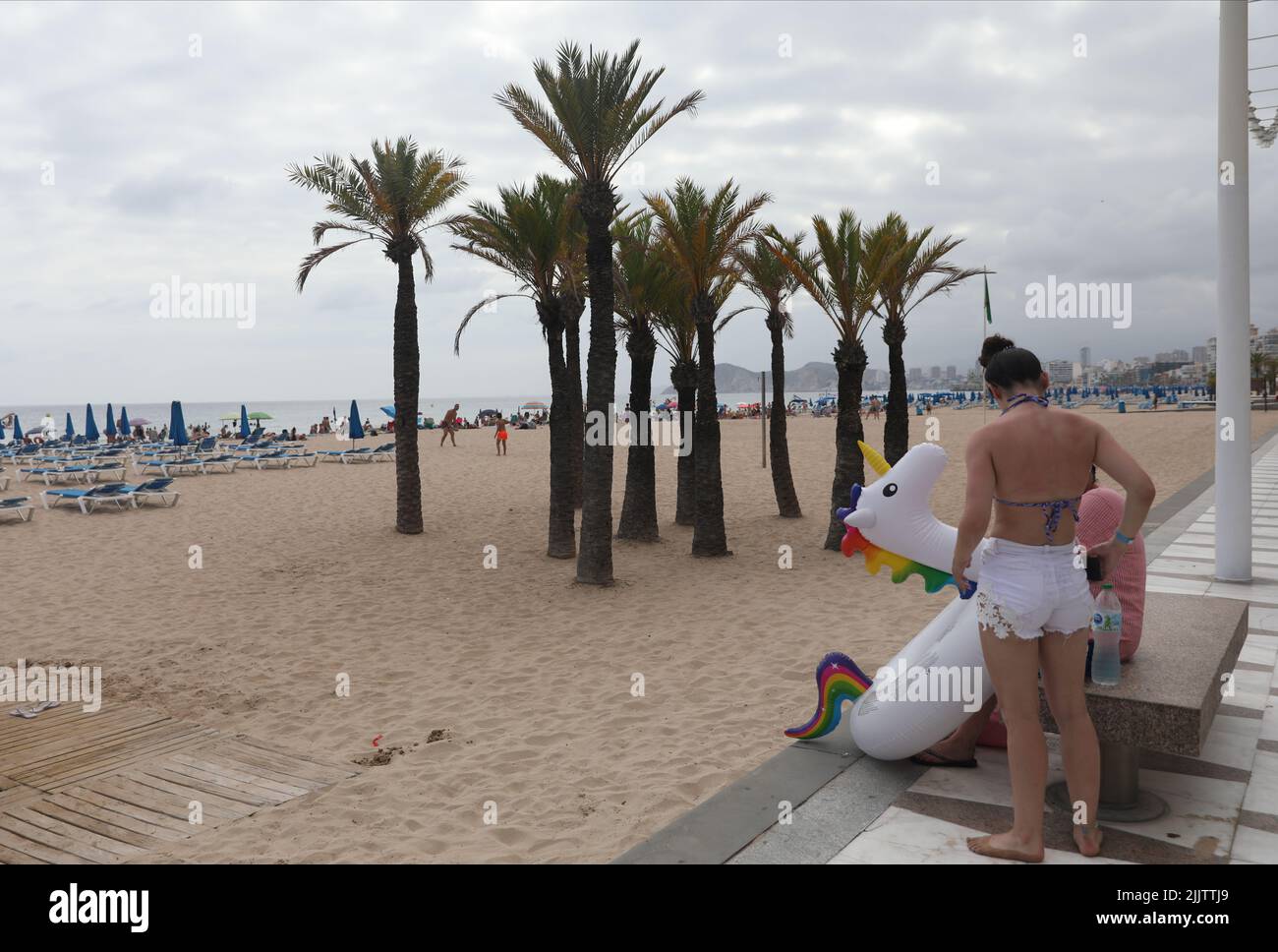Benidorm, Spagna. 27th luglio 2022. I vacanzieri trasportano un unicorno gonfiabile alla spiaggia in Benidorm, Spagna. Credito: Isabel Infantes/Alamy Foto Stock