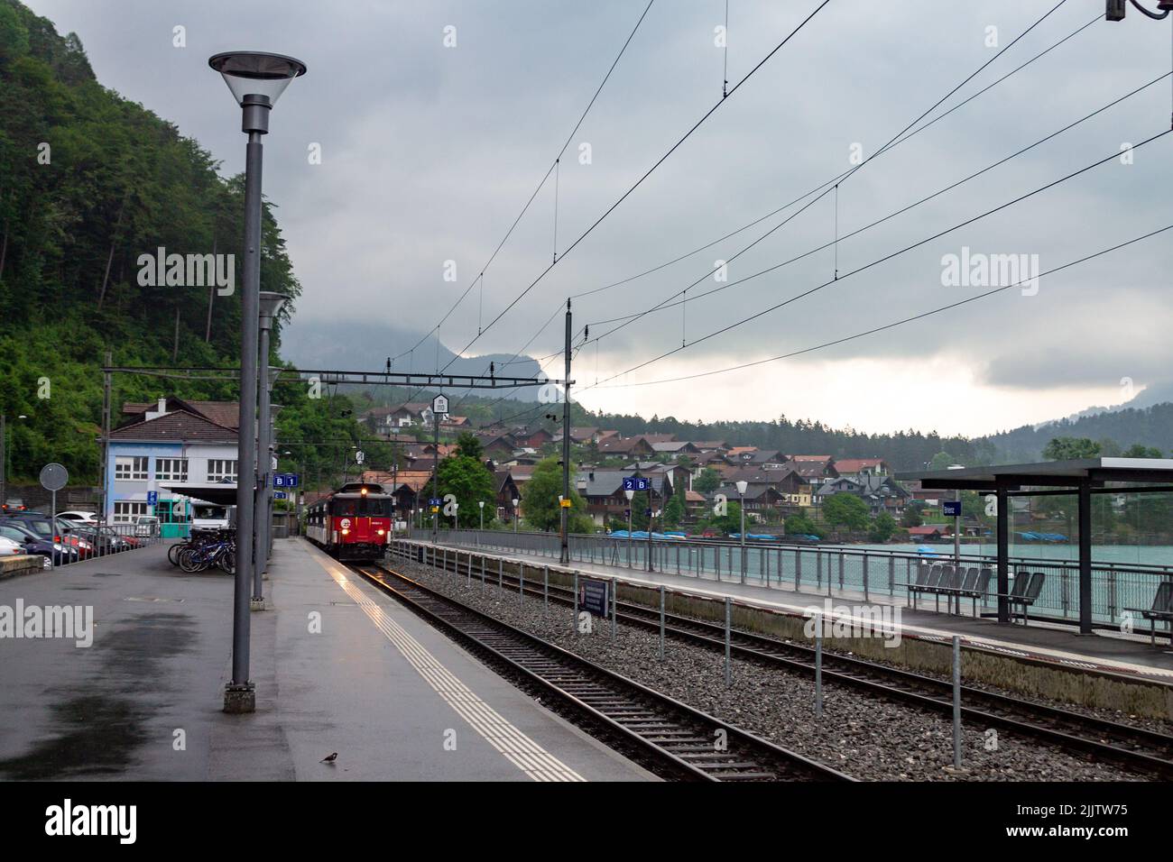 La vista della piattaforma della stazione ferroviaria esterna con il treno in arrivo. Interlaken, Svizzera. Foto Stock