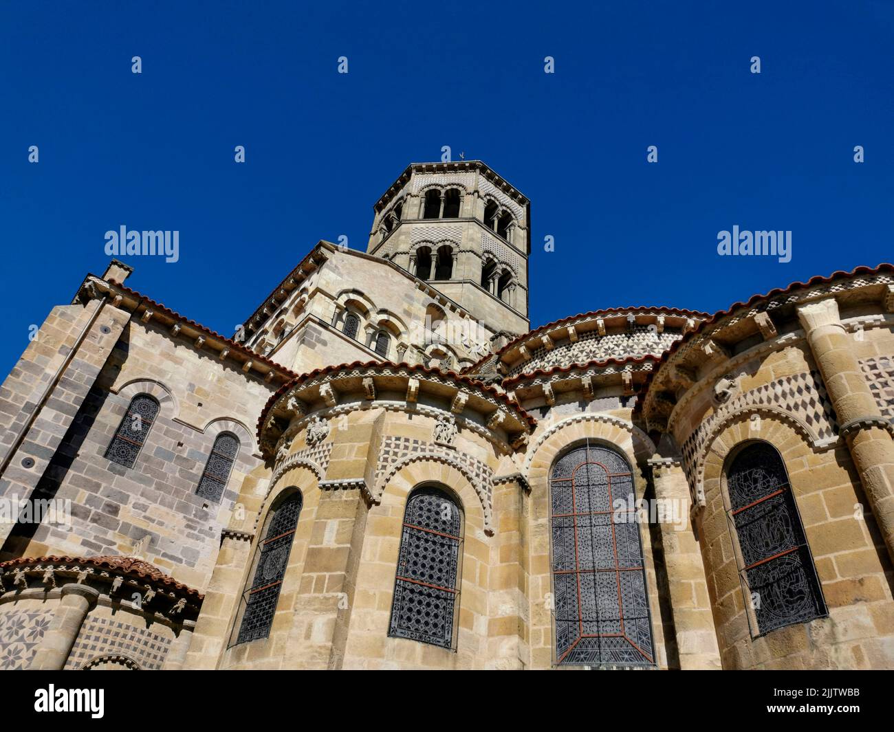 Un colpo basso angolo della chiesa abbaziale di Saint-Austremoine in Issoire con vetrate a motivi geometrici Foto Stock