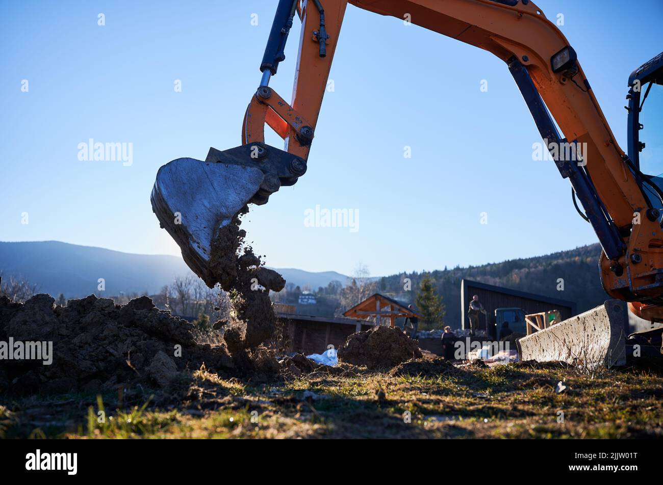 Escavatore scavare terra in cantiere in serata. Foto Stock