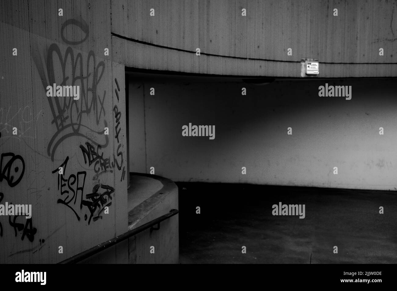 Un'immagine in scala di grigi di un tunnel pedonale con pareti dipinte da graffiti a Linz, Austria Foto Stock