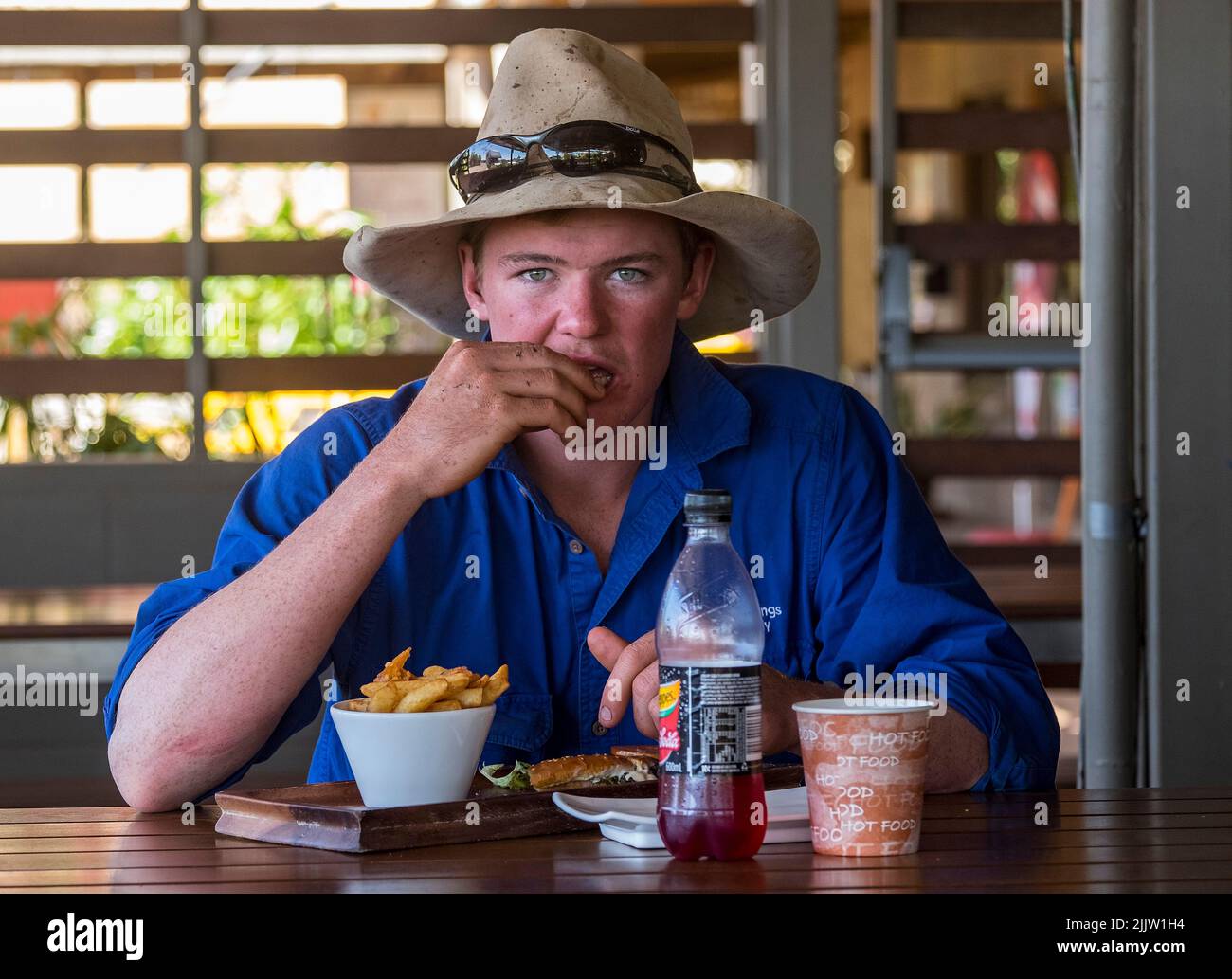 Un giovane jackaroo australiano che mangia pollo e patatine per colazione al Barkly Downs Homestead Inn in Queensland Foto Stock