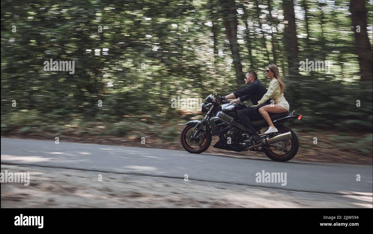 Movimento blurred giovane coppia su una moto nessun casco giro sulla strada ad alta velocità, guida pericolosa, in movimento Foto Stock