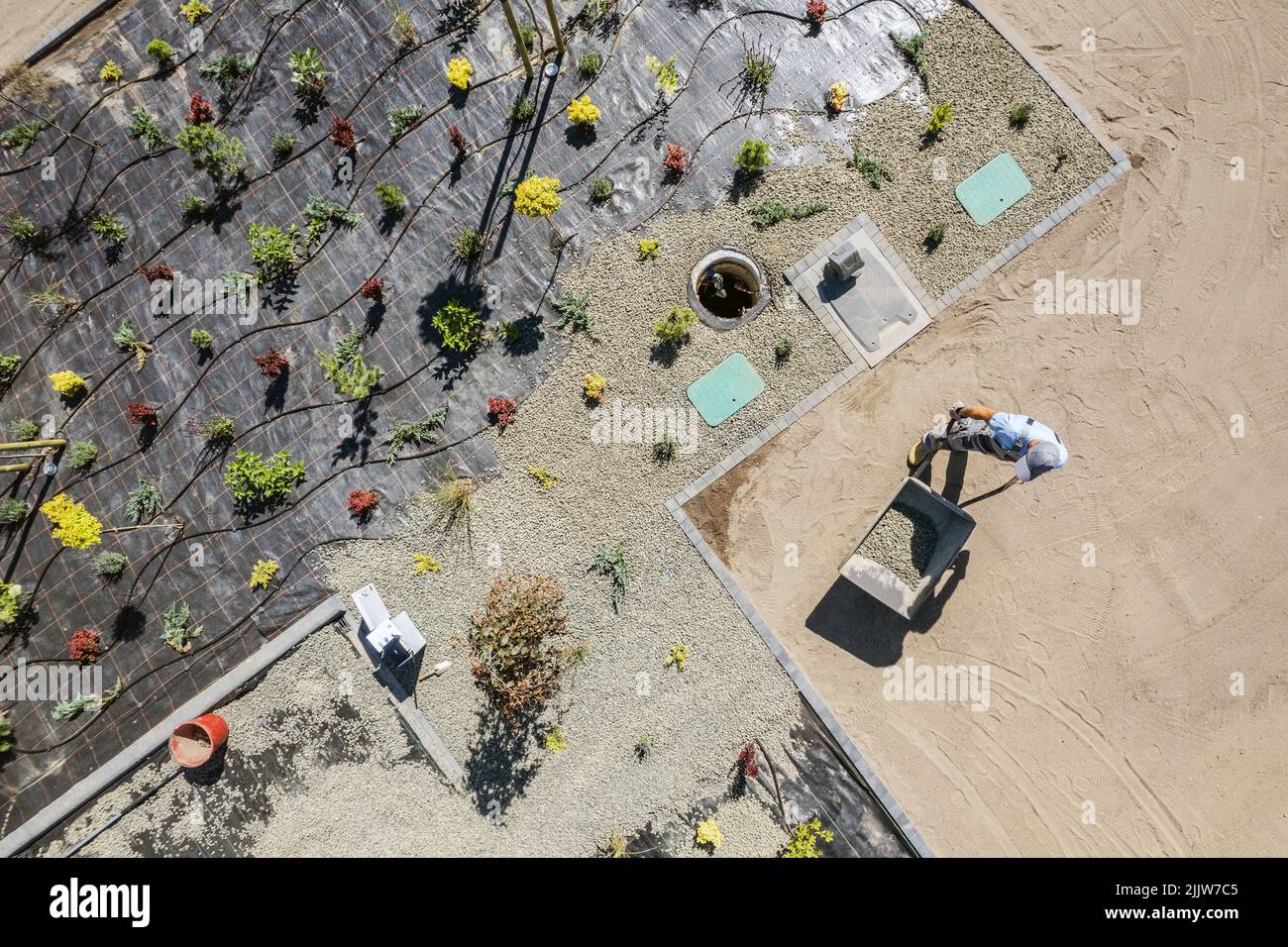 Foto aerea di paesaggista professionale Installazione di tessuto di controllo di zeppe, piantando alberi e copertura Vinyl da piccole rocce nel giardino residenziale. Foto Stock