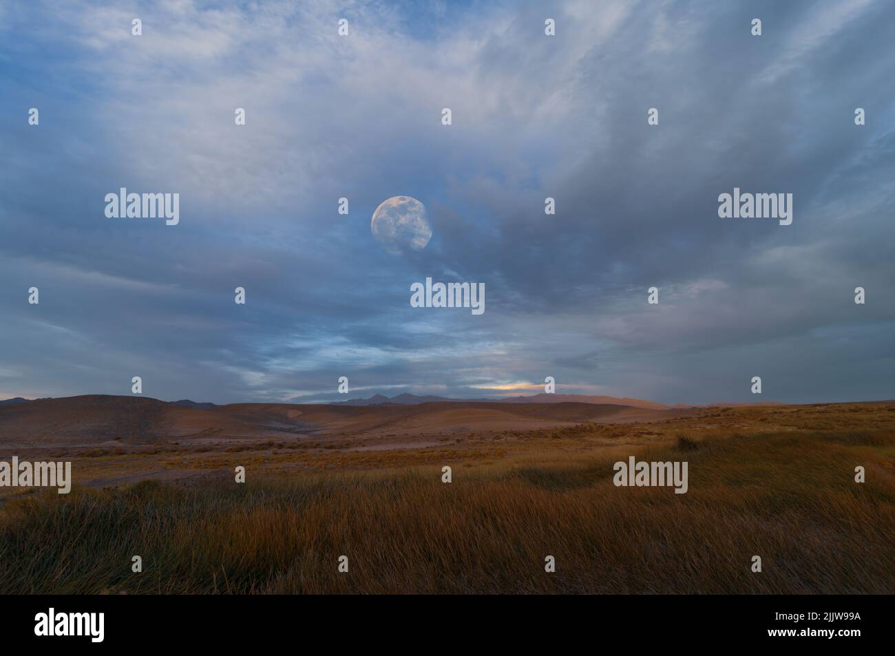 Luna che si alza contro un cielo nuvoloso mostrato nel deserto di Mojave in California. Foto Stock