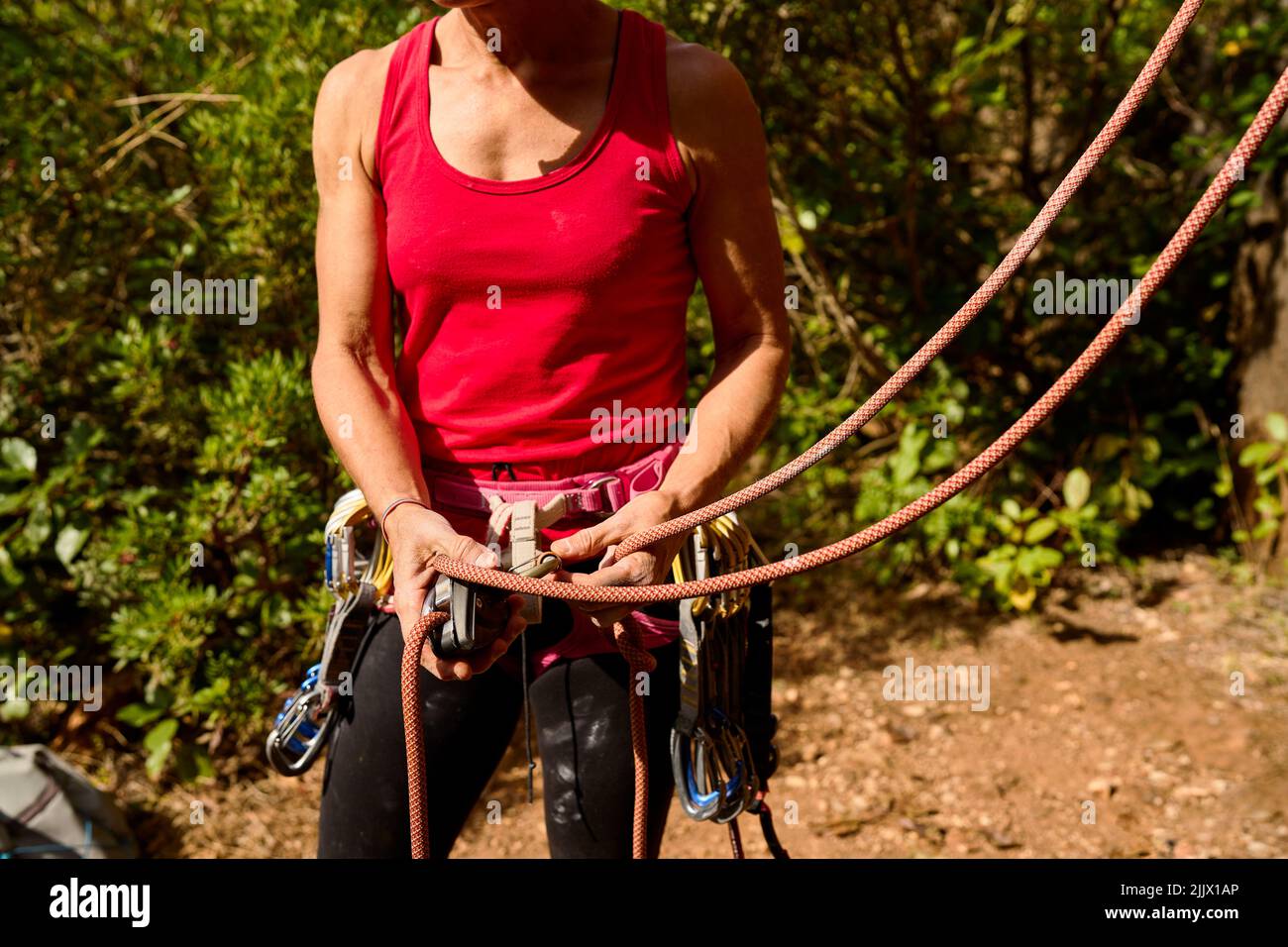 Ritagliato irriconoscibile della corda di legatura femminile attiva su imbracatura mentre si prepara per l'arrampicata Foto Stock