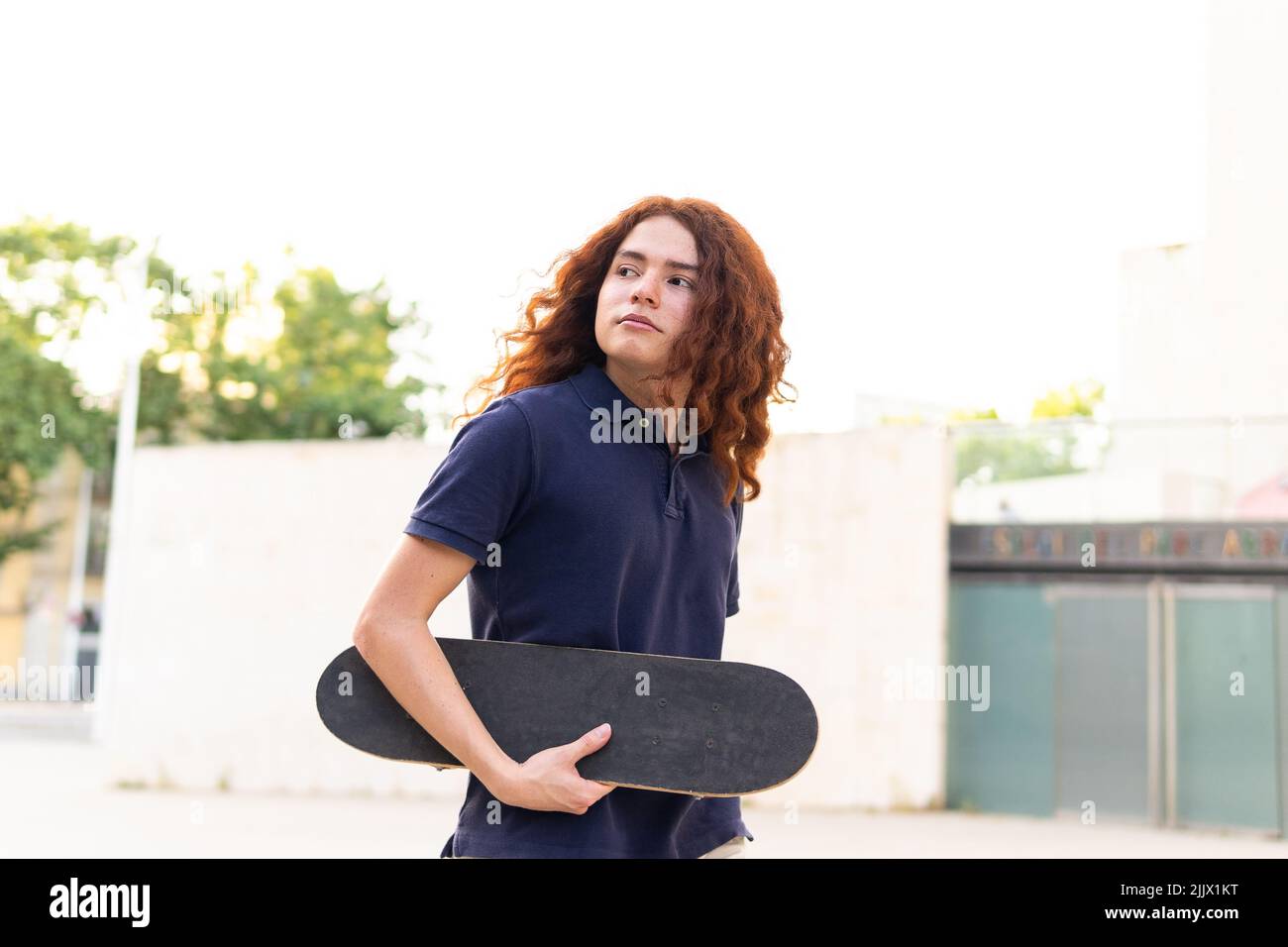 Ritratto di giovane donna con skateboard in piedi in città Foto Stock